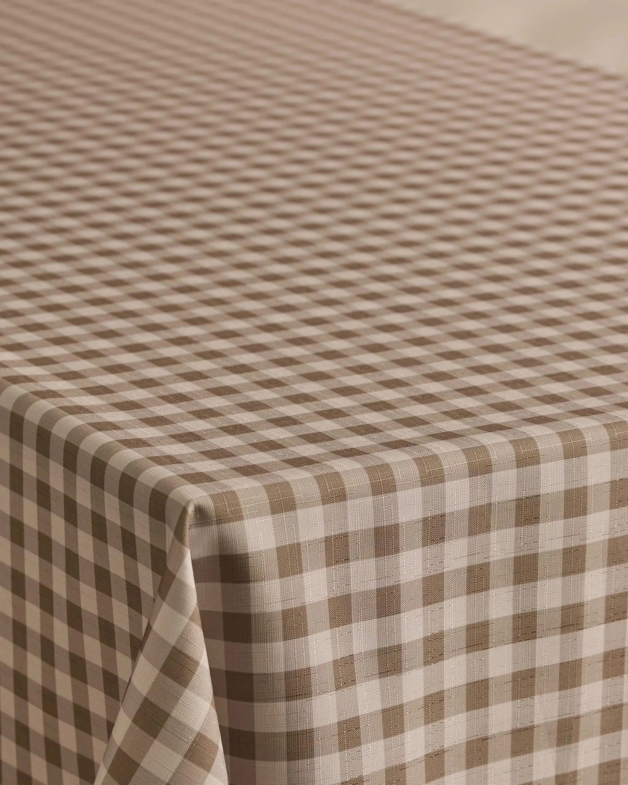 The Geometry Hazel Gingham tablecloth features a stain-resistant brown and white gingham pattern with evenly spaced diagonal checks, perfect for covering your rectangular table.