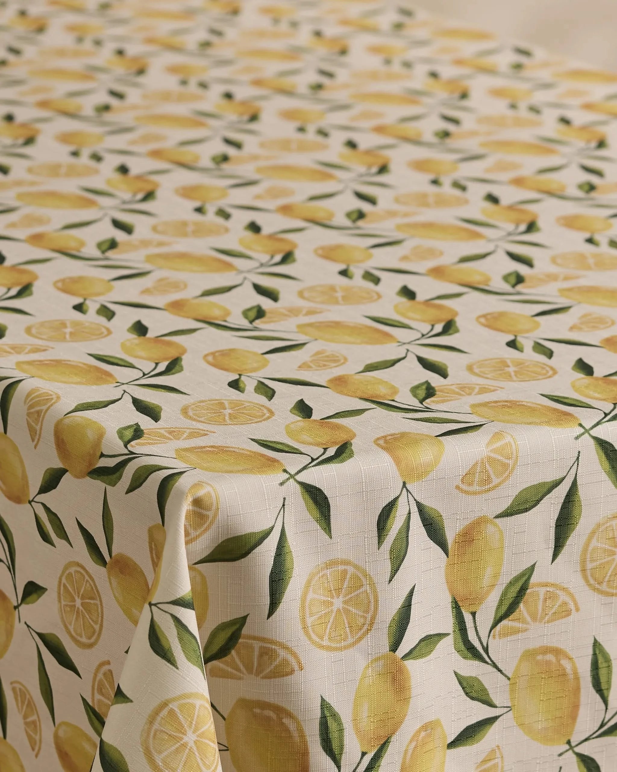 The Geometry Limoncello tablecloth has a cream background with a repeating pattern of whole lemons, lemon slices, and green leaves. Stain-resistant and stylish, its the perfect blend of function and flair for any dining space.