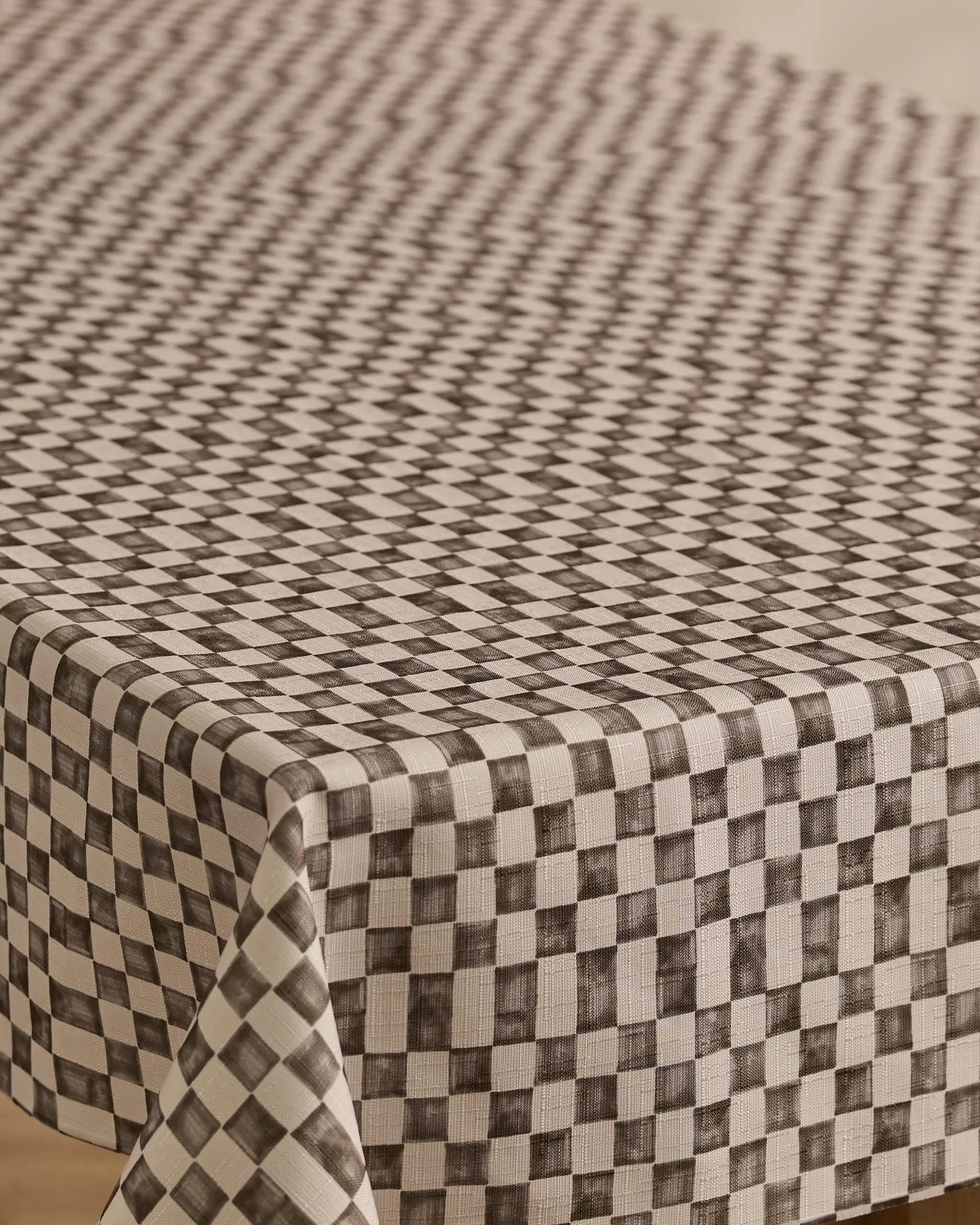 A close-up of Geometrys Tavern rectangular table covered with a stain-resistant, black and white checkered tablecloth featuring a geometric diamond pattern that creates an optical illusion effect.