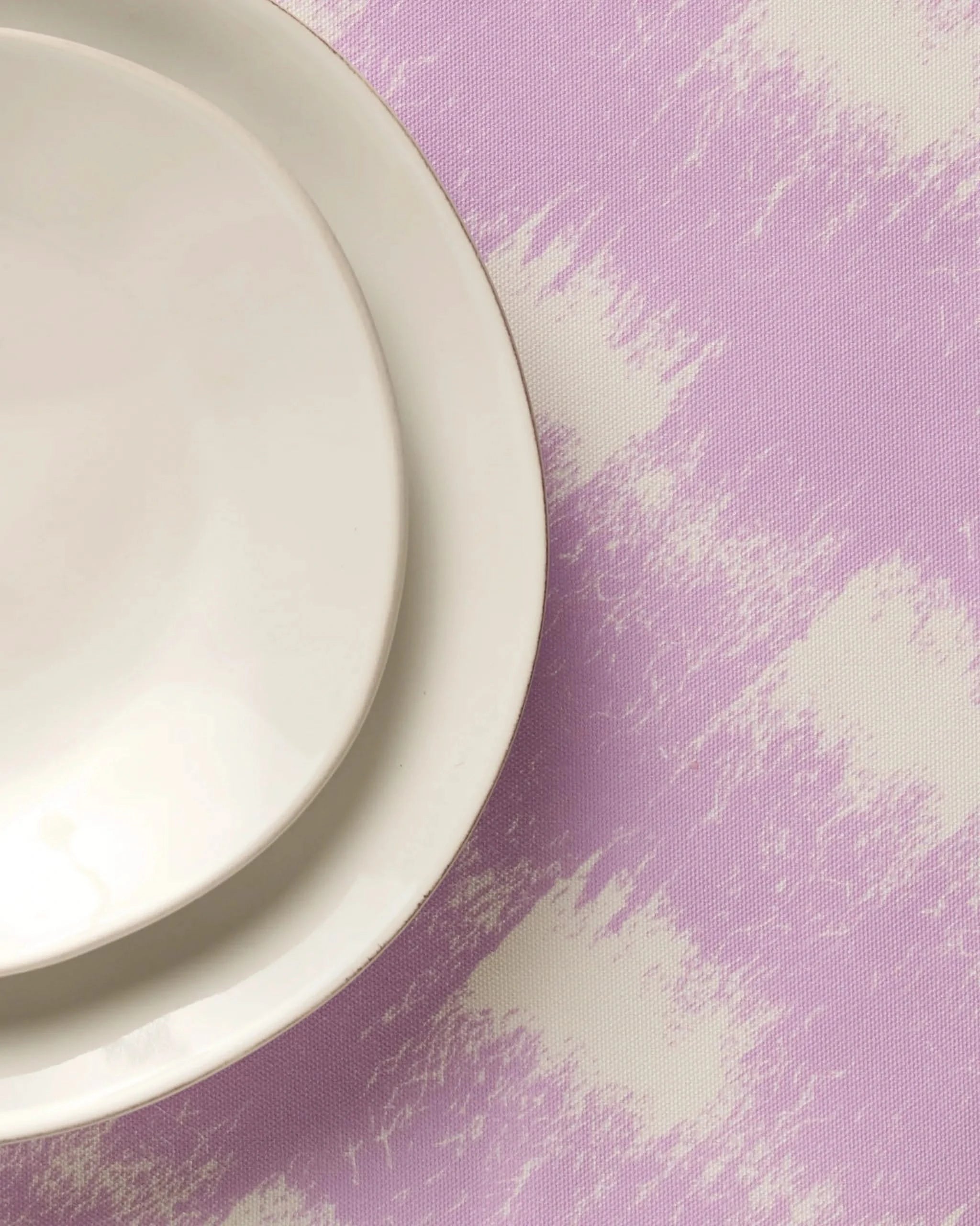 Two white ceramic plates, one small and one large, sit in the upper left corner atop the Geometry Hairy Check Pink placemat, which features a pink and white abstract pattern—perfect for adding a stylish touch to your table.