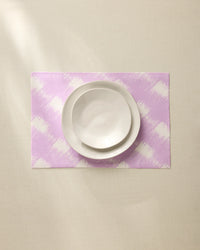 A white bowl and plate are stacked on the Geometry Hairy Check Pink recycled placemat, set on a light beige surface under soft lighting.