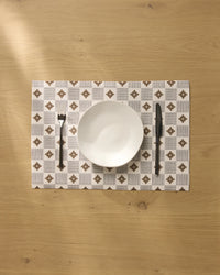 A white bowl is placed on the Geometry Legacy Block placemat, with a fork to the left and a knife to the right, all neatly arranged on a light wooden table.