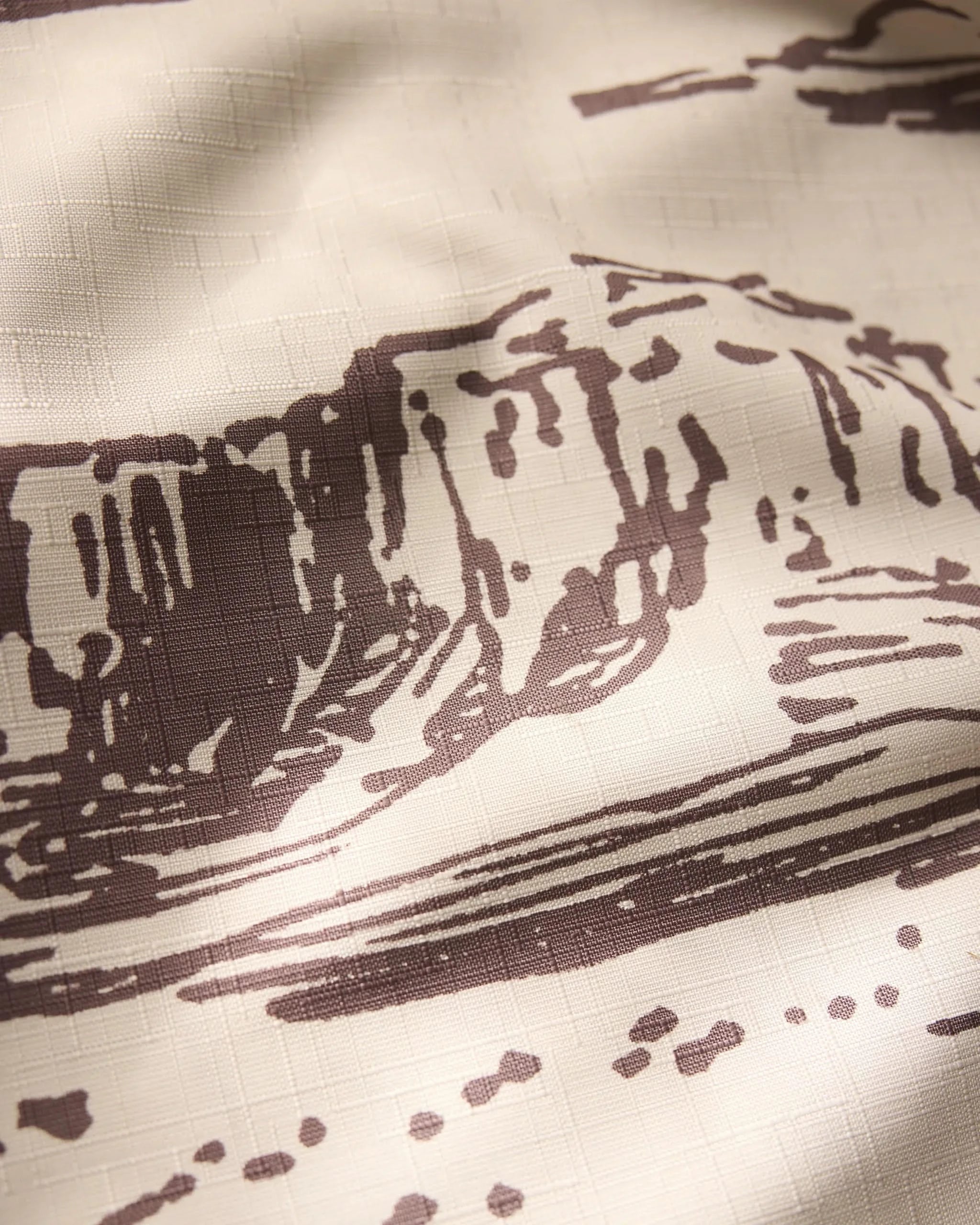 The Geometry Western Scene features a close-up of beige fabric with a brown landscape print of abstract rock formations and textured grids—ideal as a lightweight tablecloth for adding subtle, artistic style.