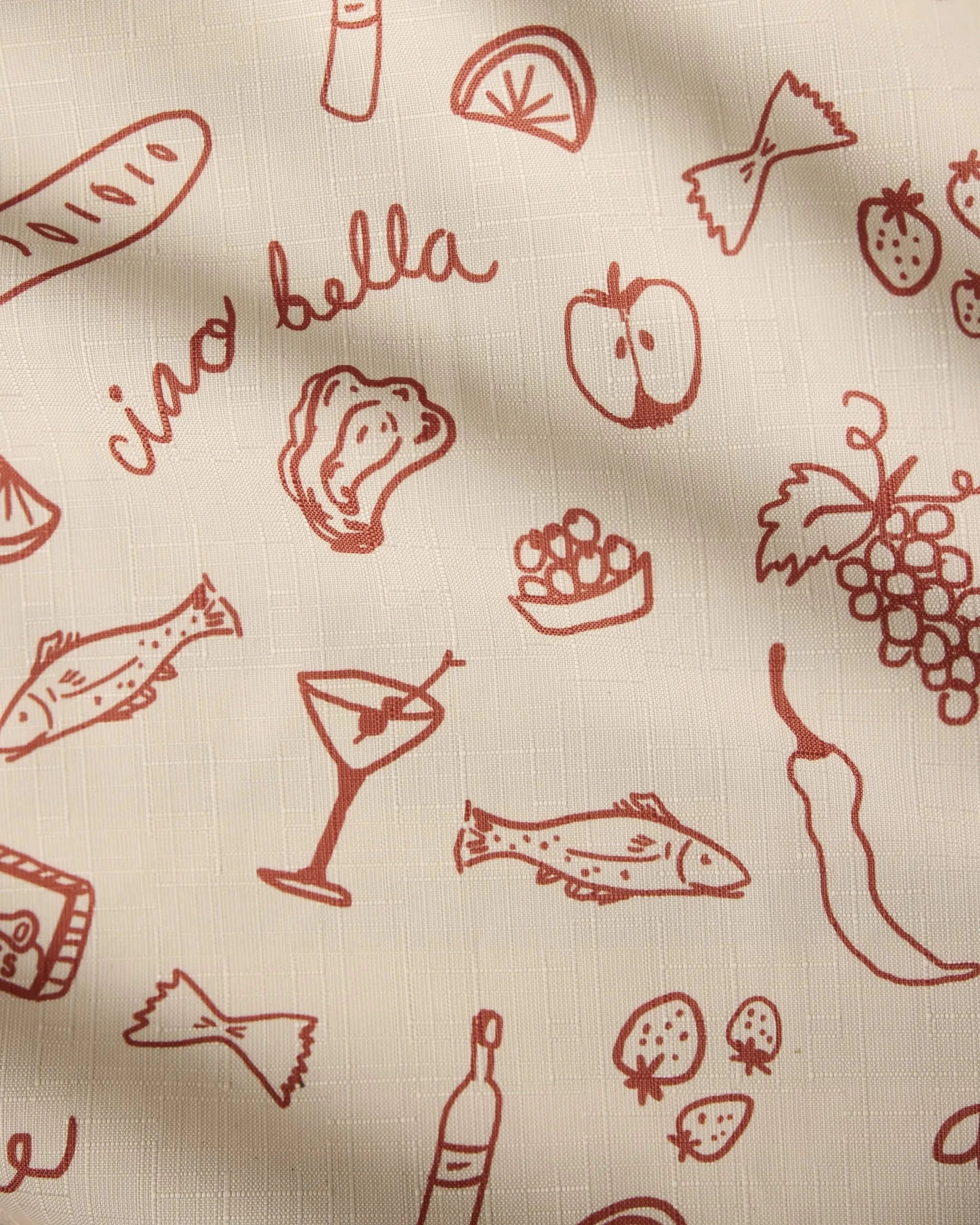 Geometry’s “Summer Air” is a cream-colored, recycled tablecloth featuring red line art of Italian foods like fish, grapes, oysters, pasta, bread, and drinks with the phrase “ciao bella.” It’s stain-resistant and beautifully textured with light shadows.
