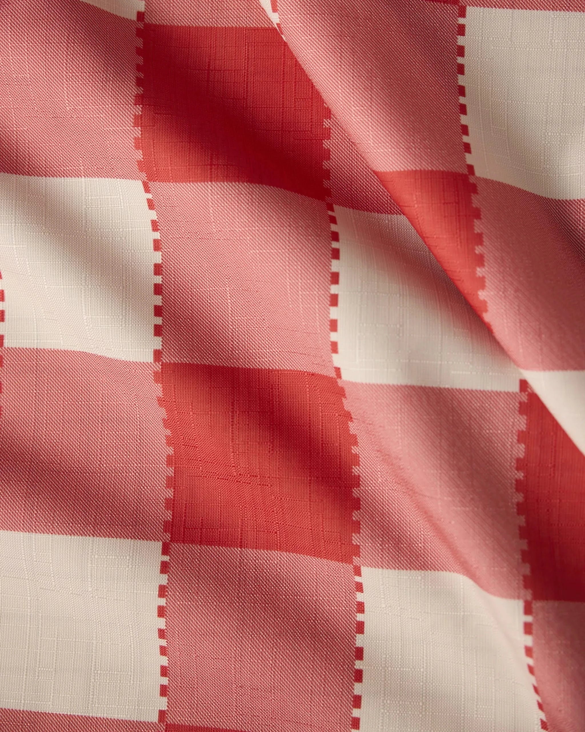 A close-up of Geometry’s Ripe Tomato Gingham fabric, showcasing its red and white checkered pattern and soft texture—ideal for a stain-resistant tablecloth.