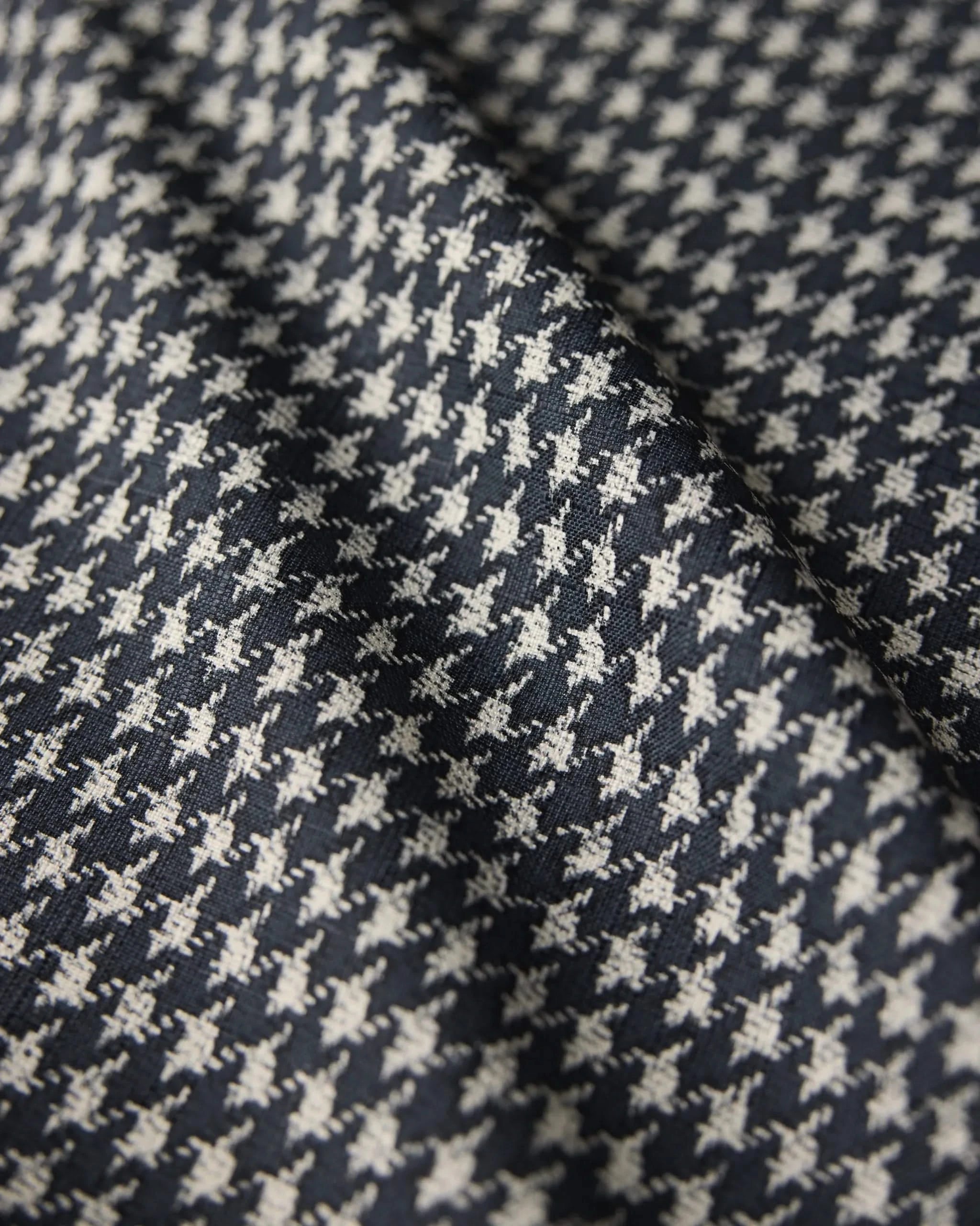Close-up of Houndstooth Black by Geometry, featuring a black and white houndstooth pattern. The fabric’s diagonal fold highlights its weave and texture—ideal for a stylish, stain-resistant table runner.