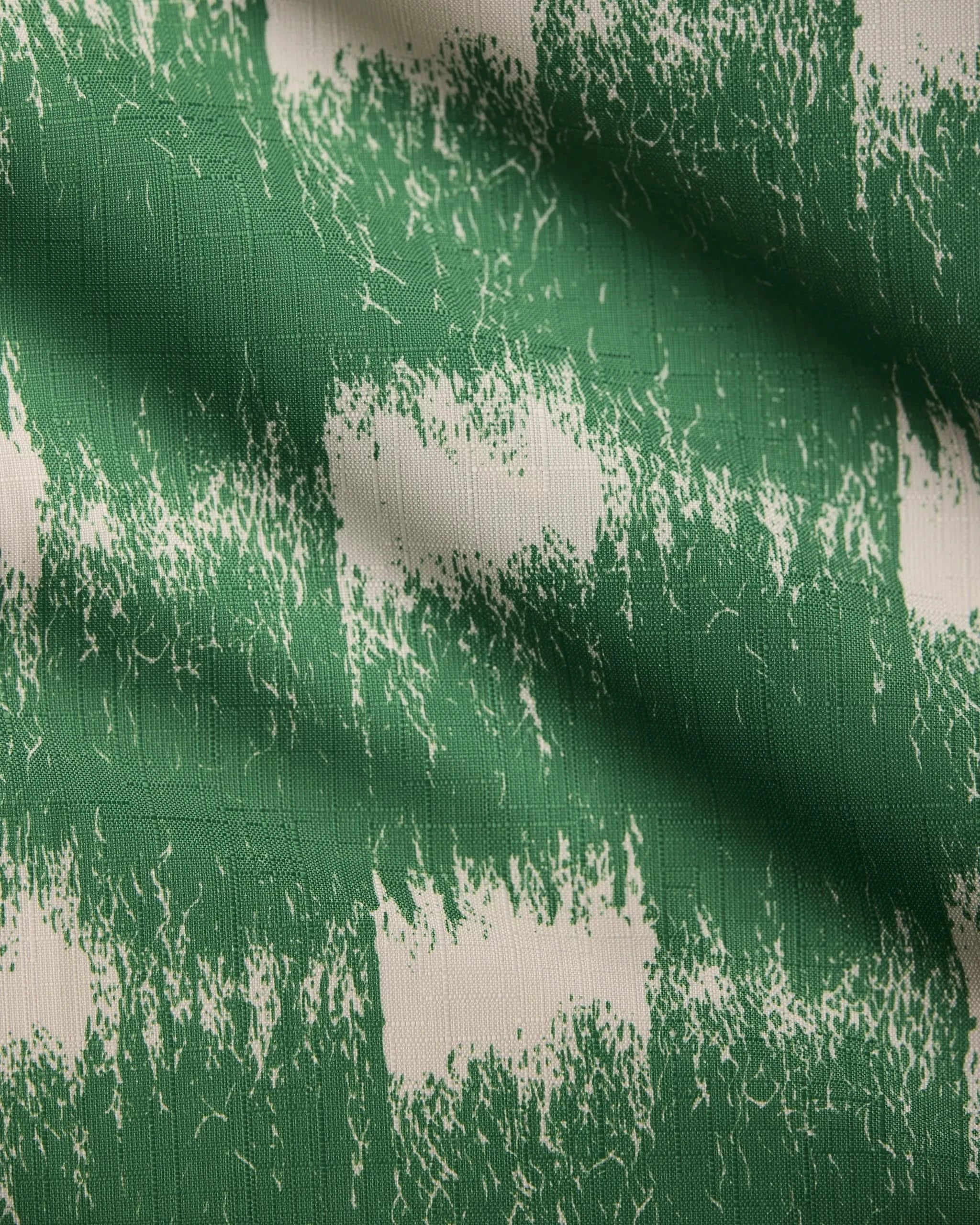 The Hairy Check Green tablecloth by Geometry features a green and white checkered pattern with textured, painted effects, rough-edged green stripes, visible fabric weave, and light creases for a unique look.