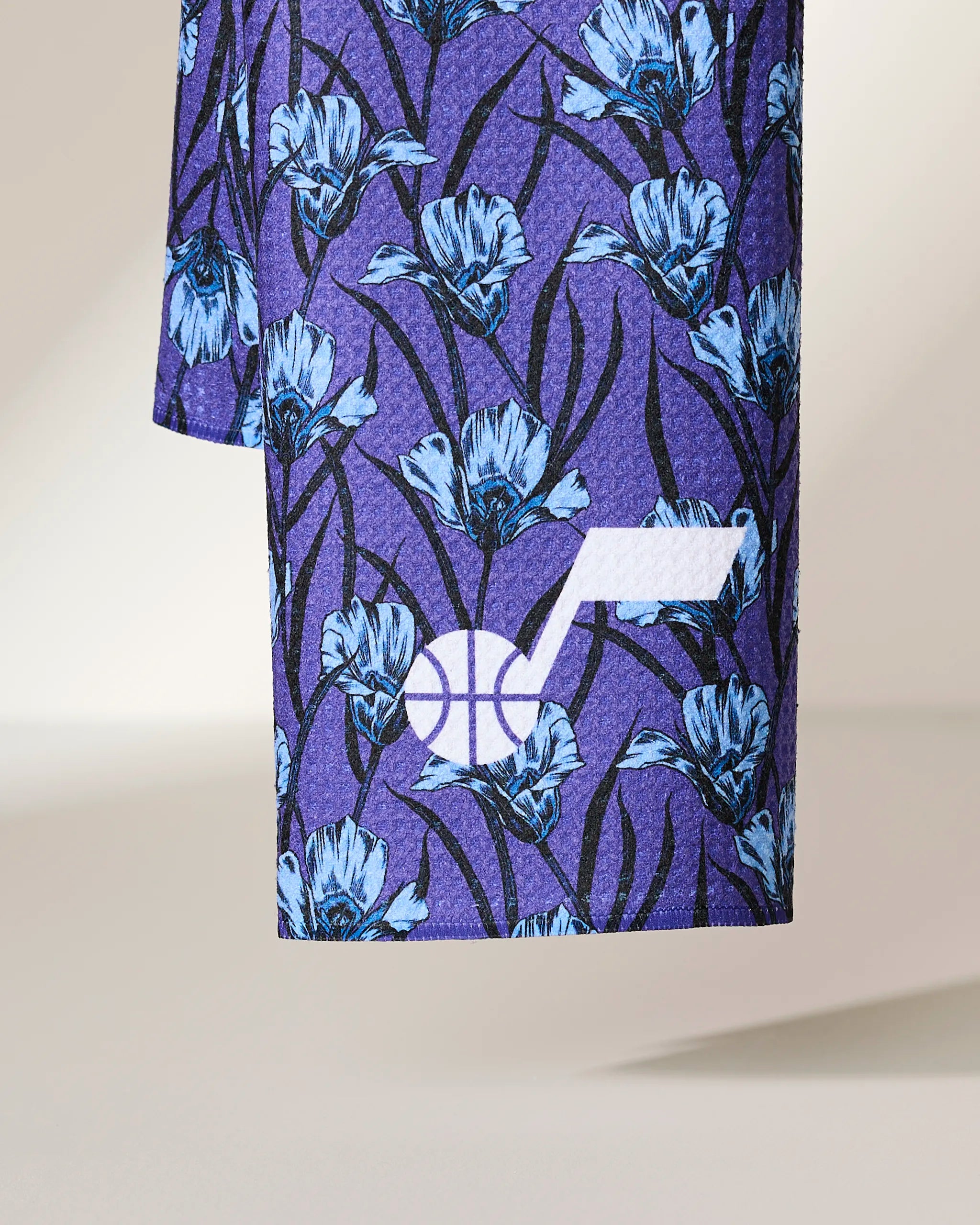A close-up of the Geometry Jazz Floral fabric showcases a blue floral pattern on purple, with a white Utah Jazz basketball logo near the bottom right.