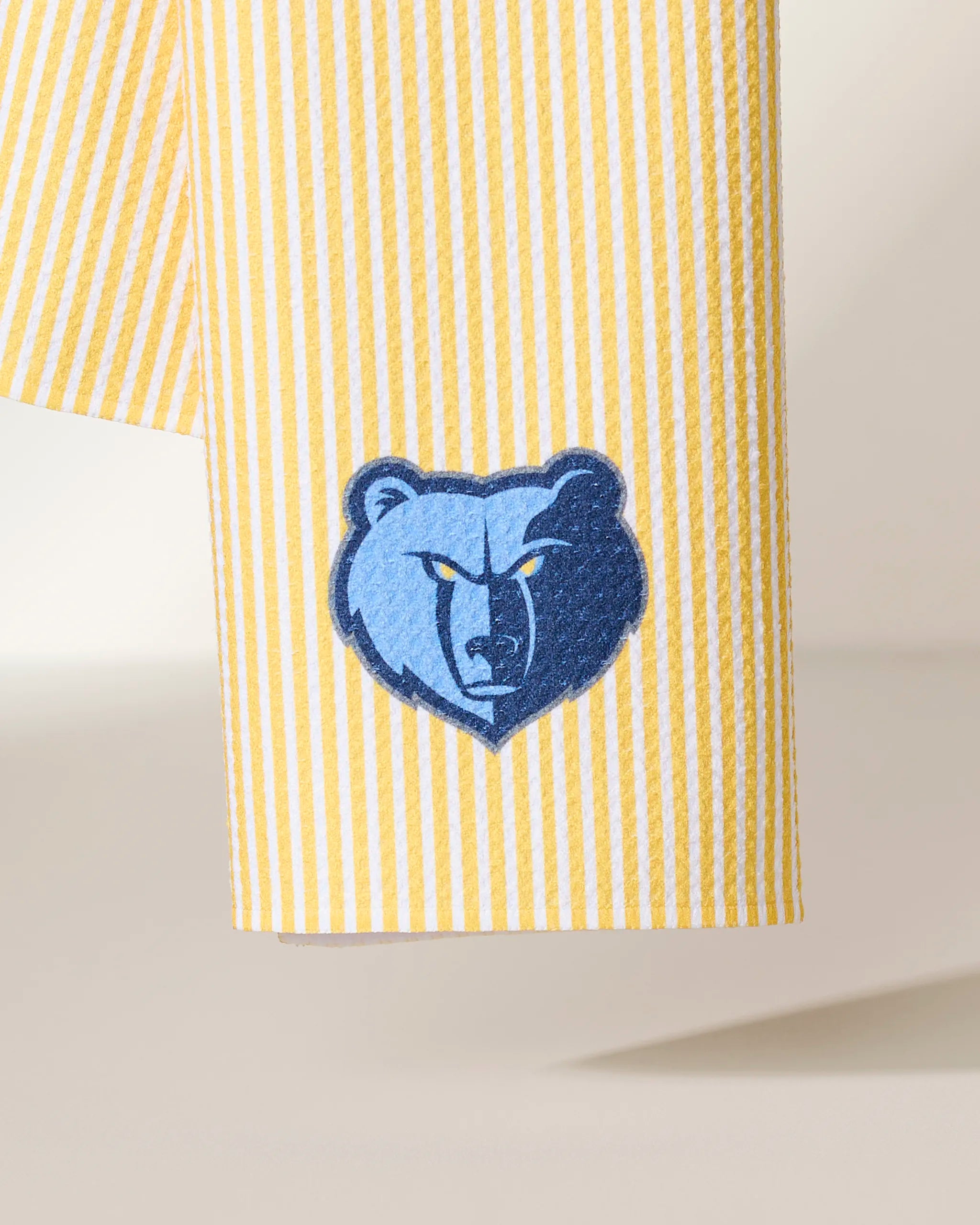 The Geometry Grizzlies Classic features yellow and white vertical stripes with an embroidered blue bear head logo showing a fierce expression near the hem.