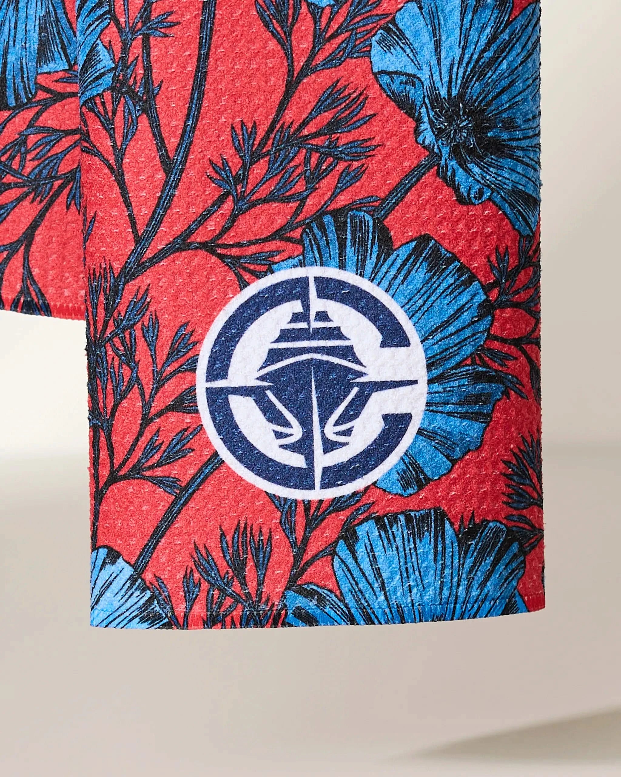 A close-up of Clippers Floral by Geometry shows red fabric with blue flowers and black stems, accented by a round white and blue abstract logo at the center.
