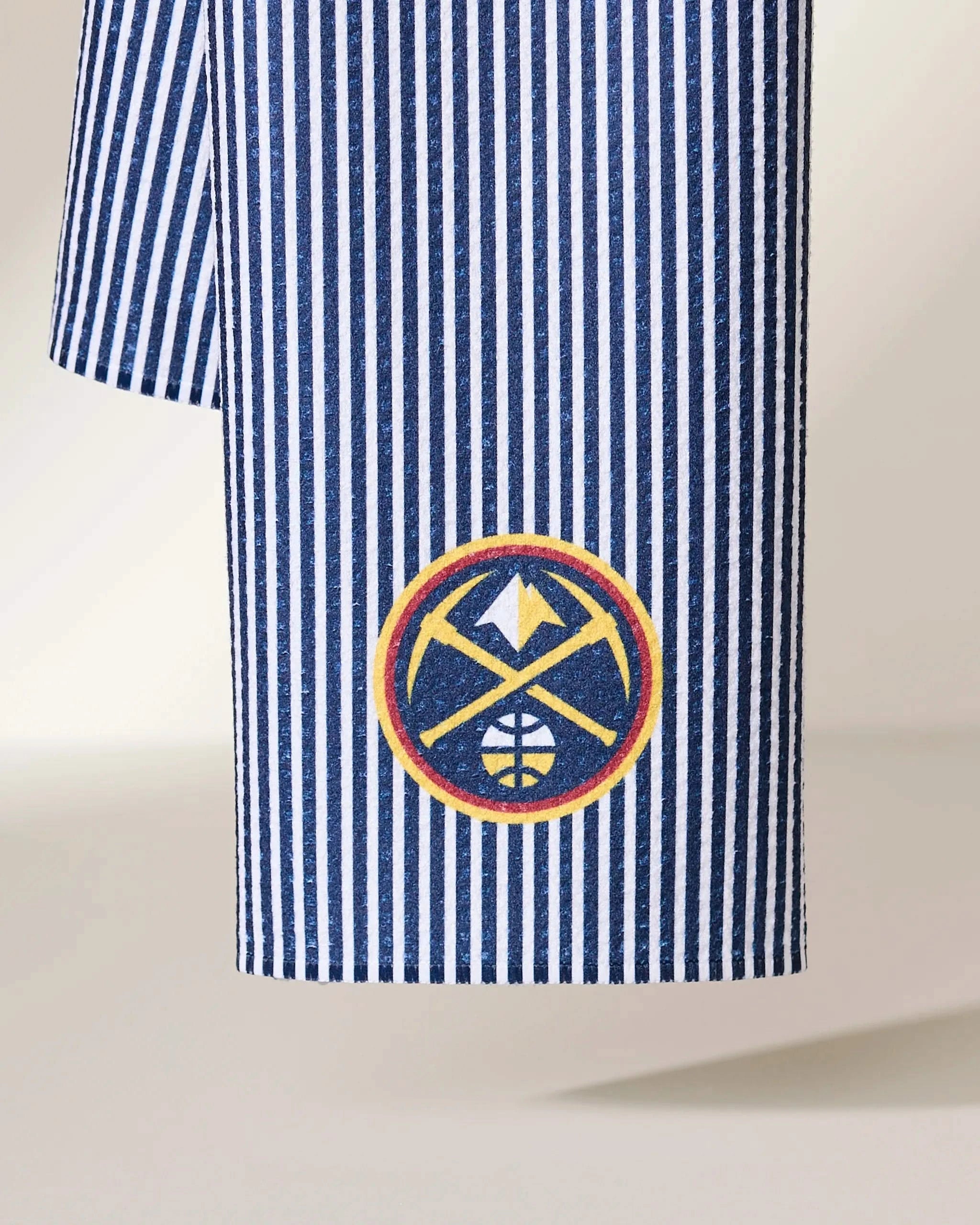 A close-up of the Geometry Nuggets Classic blue and white vertical striped fabric, featuring the Denver Nuggets basketball team logo embroidered near the bottom.