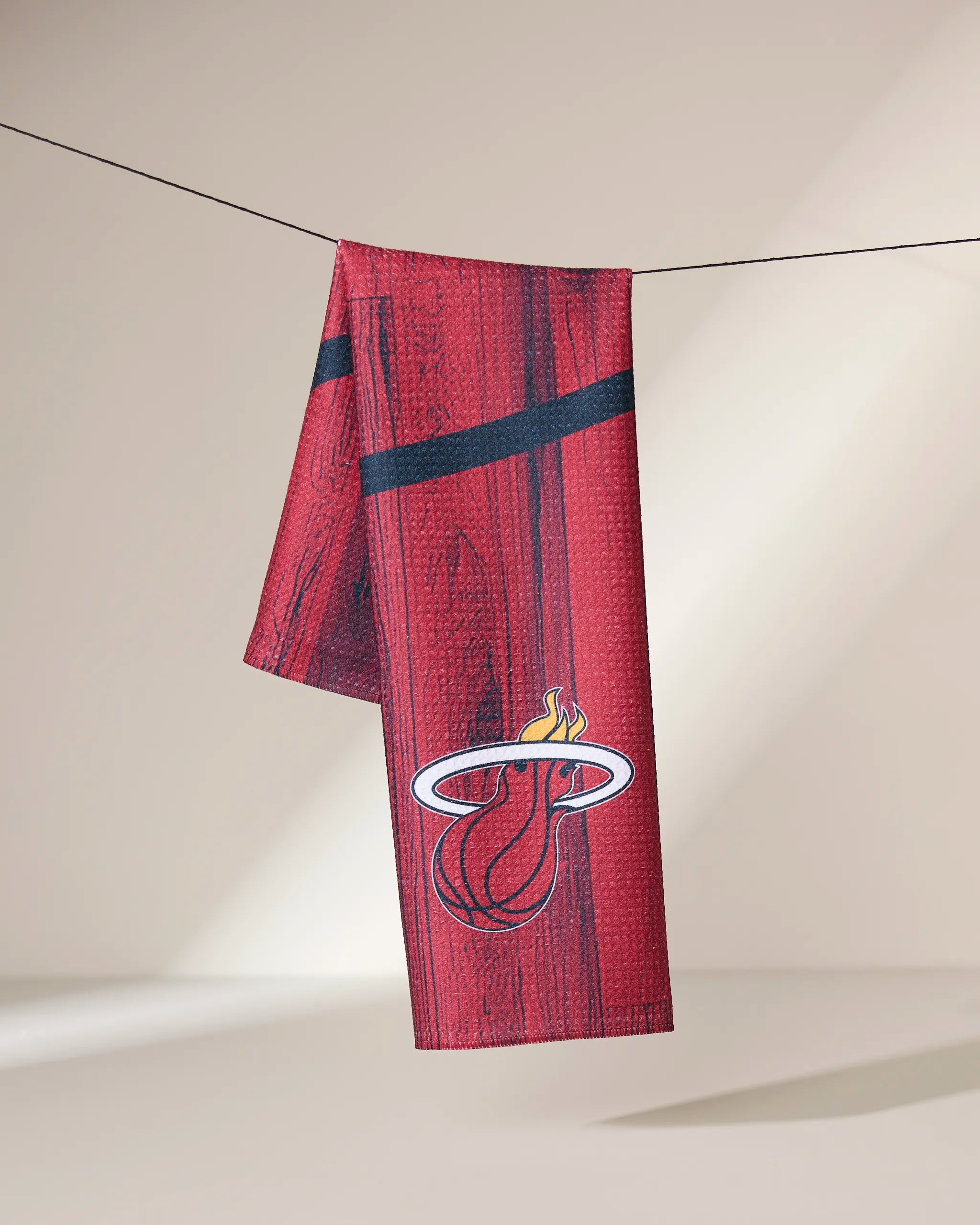 The Geometry Heat Zone towel, featuring the Miami Heat logo, hangs draped over a clothesline against a neutral background.