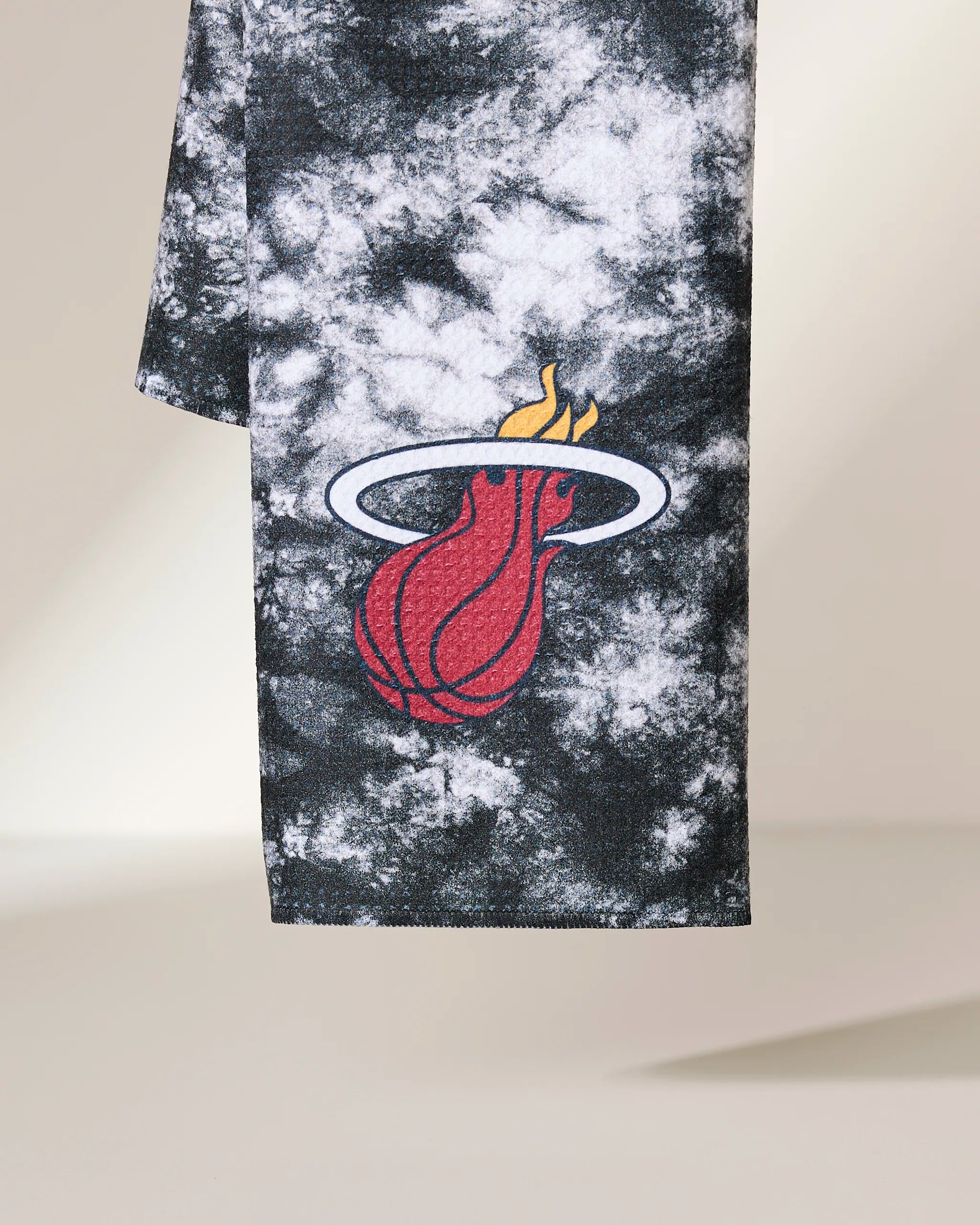 The Heat Flash by Geometry is a black and white tie-dye fabric featuring the Miami Heat logo, which displays a flaming basketball passing through a white hoop.