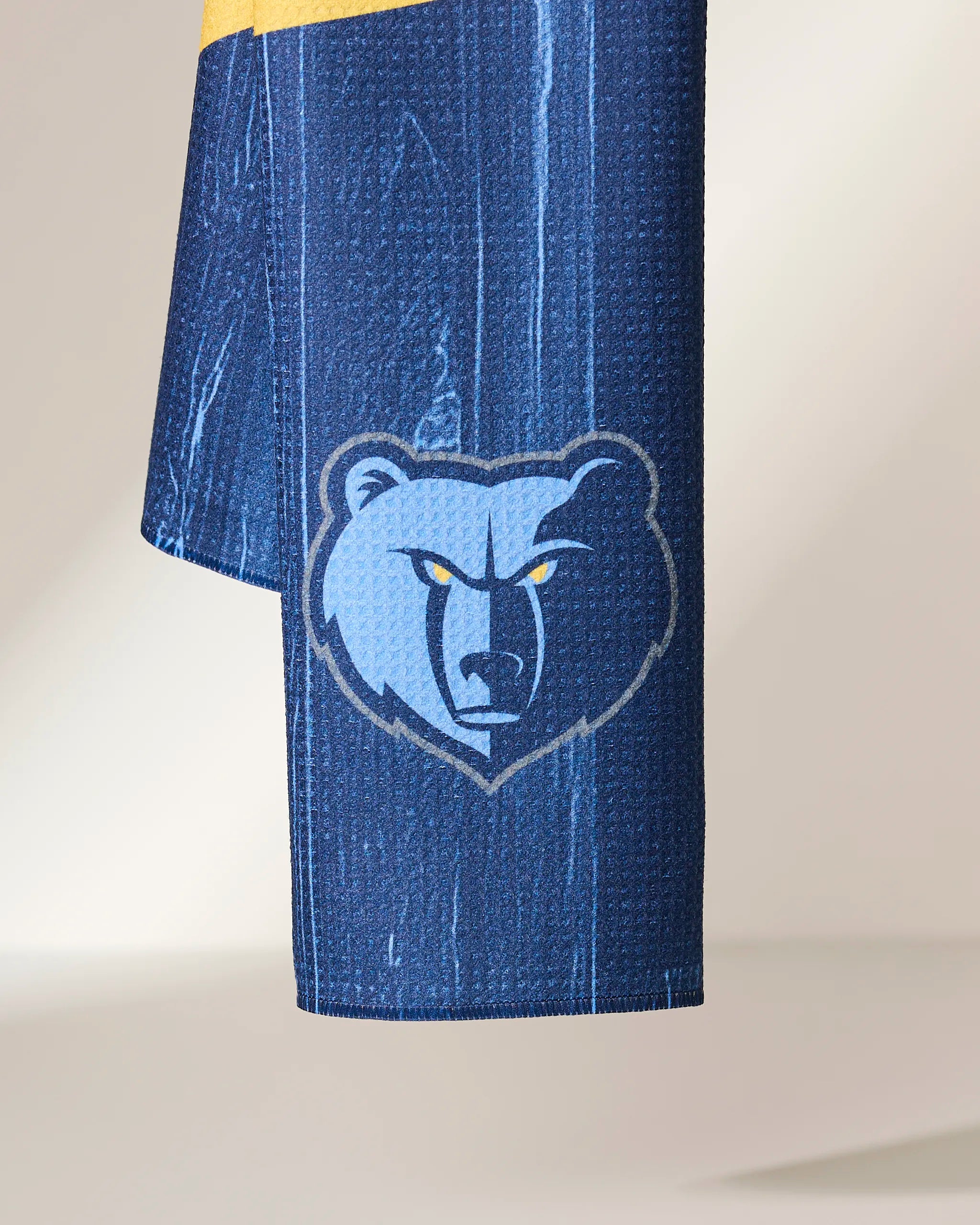 A close-up of the Grizzlies Zone by Geometry shows blue textured fabric with the Memphis Grizzlies stylized bear face logo and vivid yellow eyes.