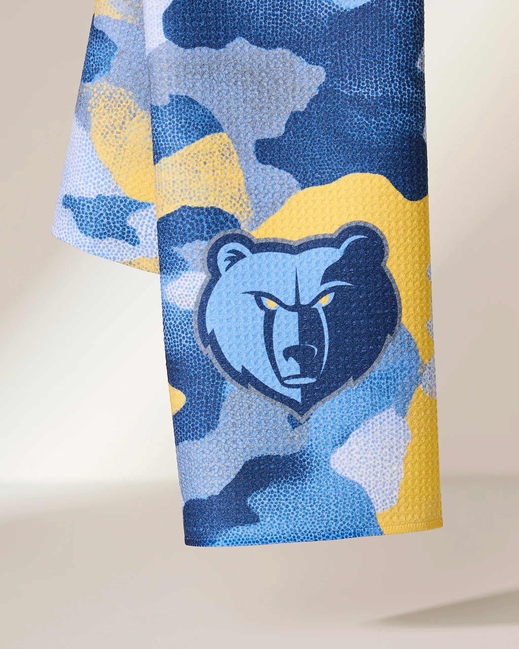 A close-up of the Grizzlies Camo towel by Geometry, featuring a blue, yellow, and white camouflage pattern with the Memphis Grizzlies bear logo in the center.