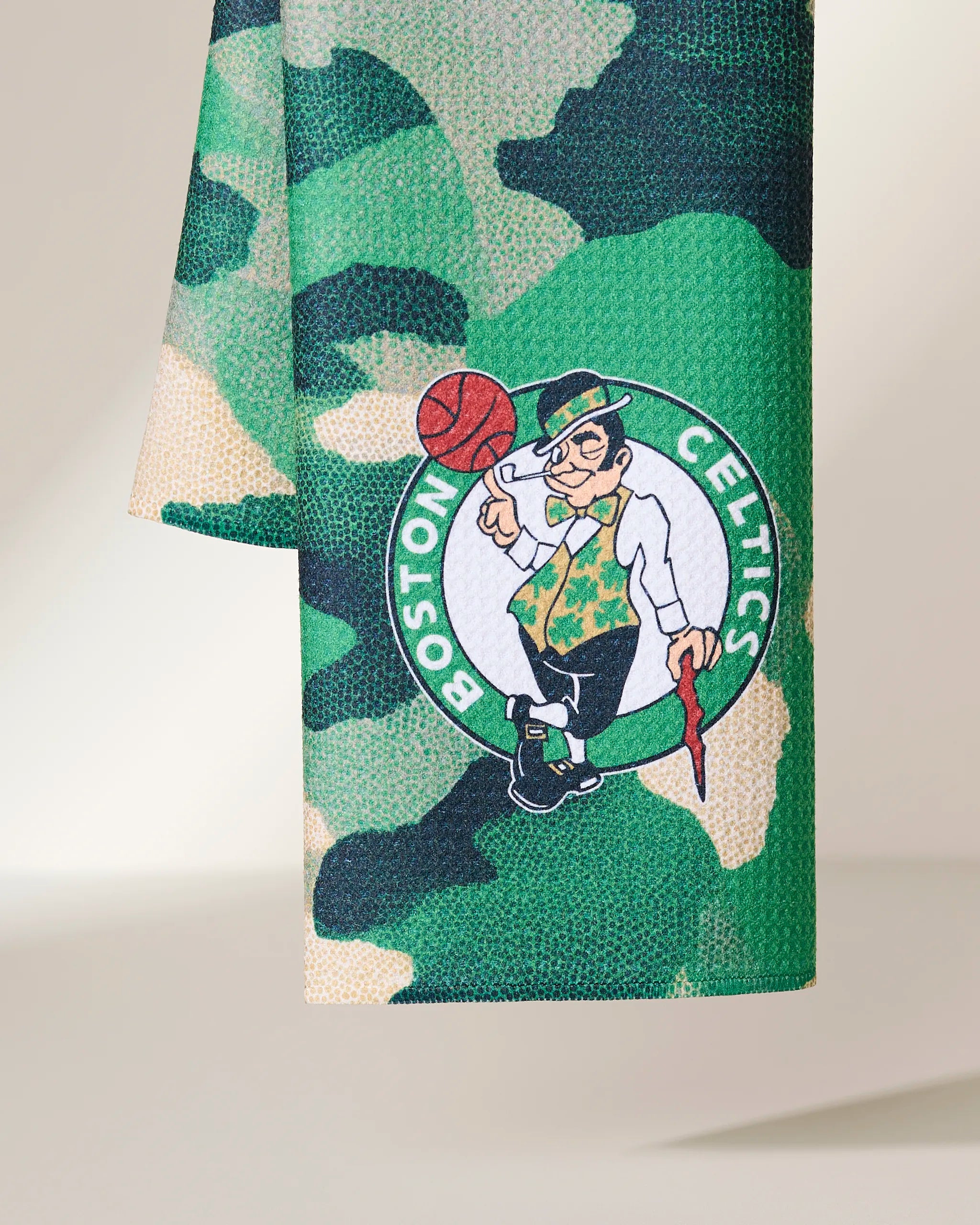 A close-up of Geometry’s Celtics Camo fabric shows a green camouflage pattern with the Boston Celtics logo featuring a leprechaun spinning a basketball.