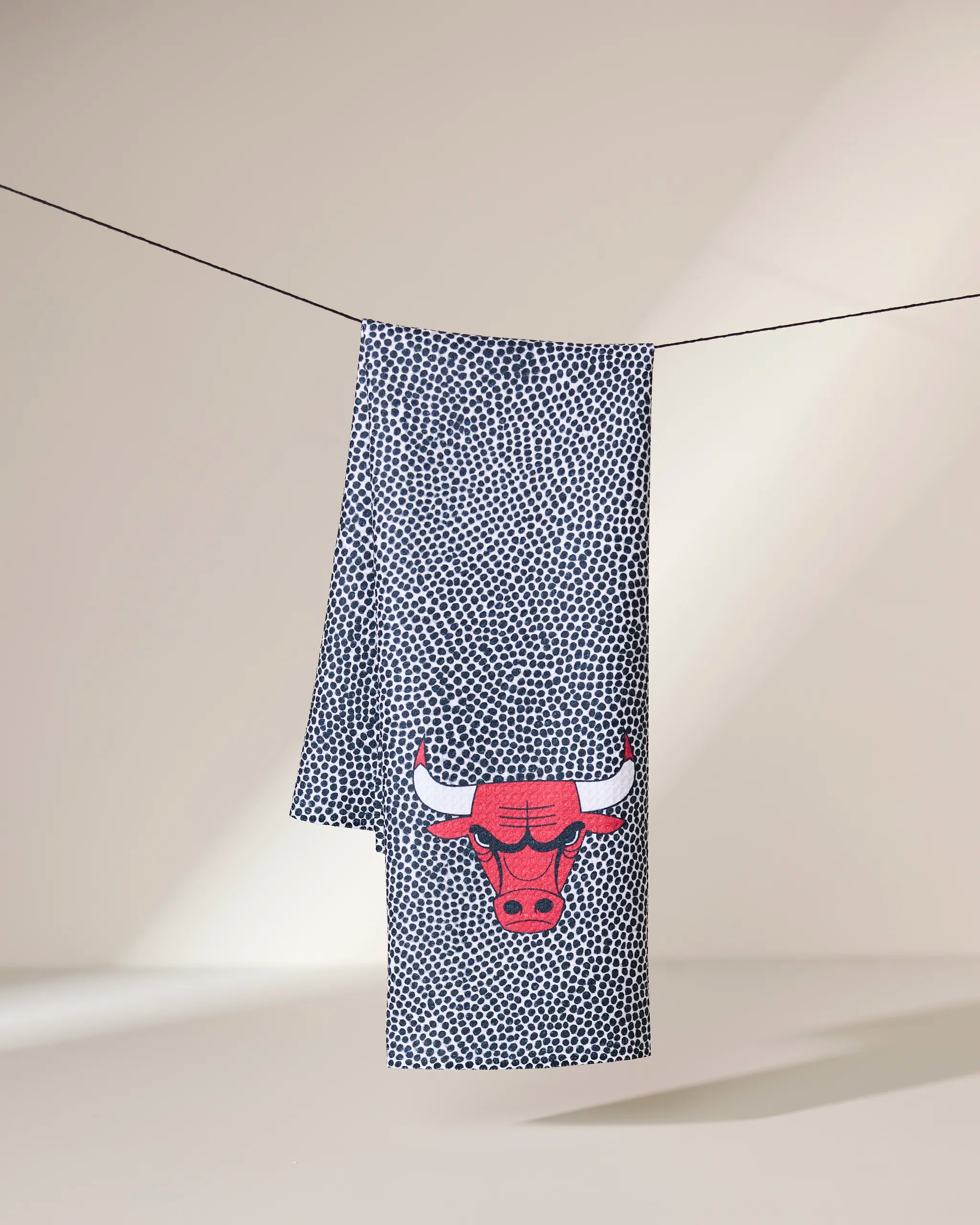 The Geometry Bulls Grip tea towel, made from quick-drying recycled materials, features a blue and white pattern with the Chicago Bulls red bull logo in the corner.