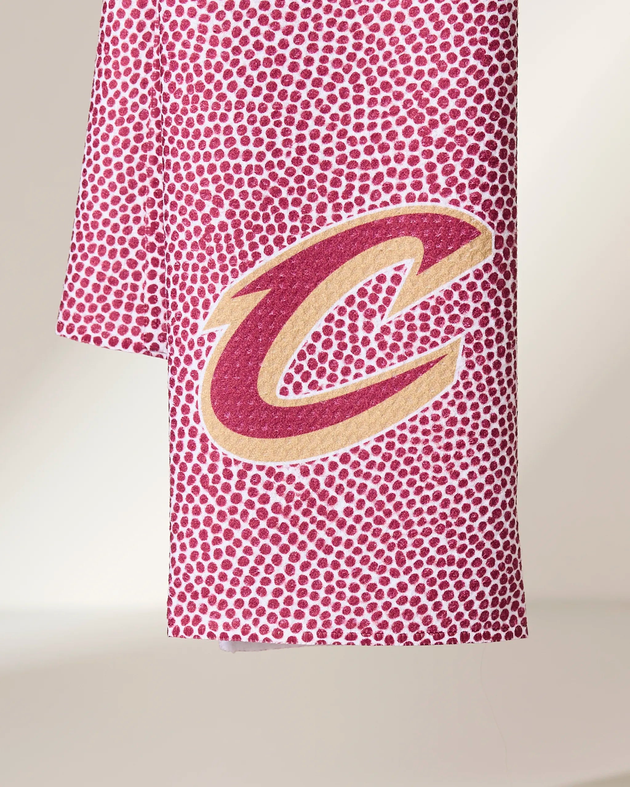 The Geometry Cavaliers Grip Red towel features a maroon and gold Cleveland Cavaliers C logo on white fabric with a pattern of small maroon dots.