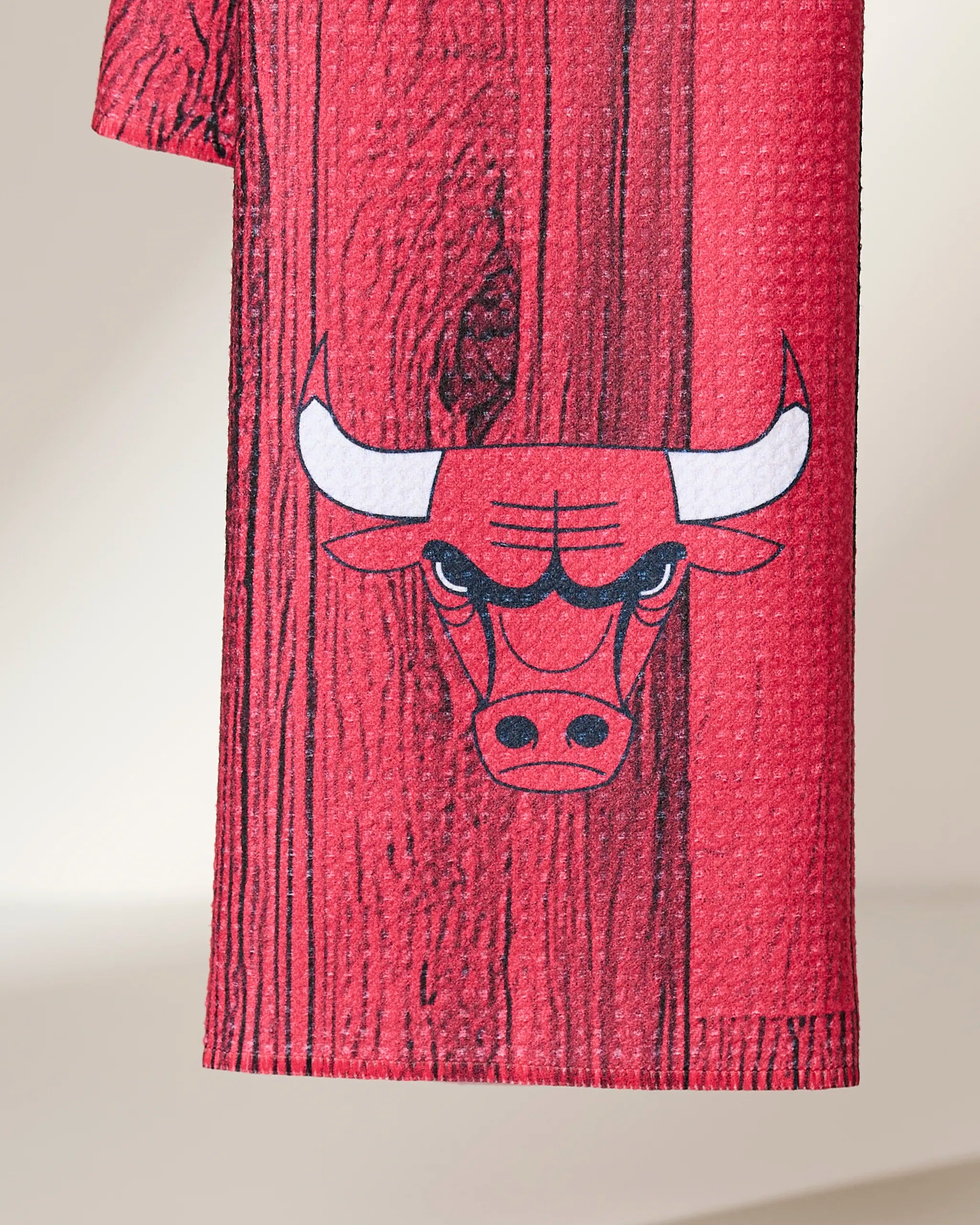 A close-up of the Geometry Bulls Zone recycled kitchen towel, designed with a woodgrain pattern and featuring the Chicago Bulls logo—a red bull’s face with white horns and an intense expression.