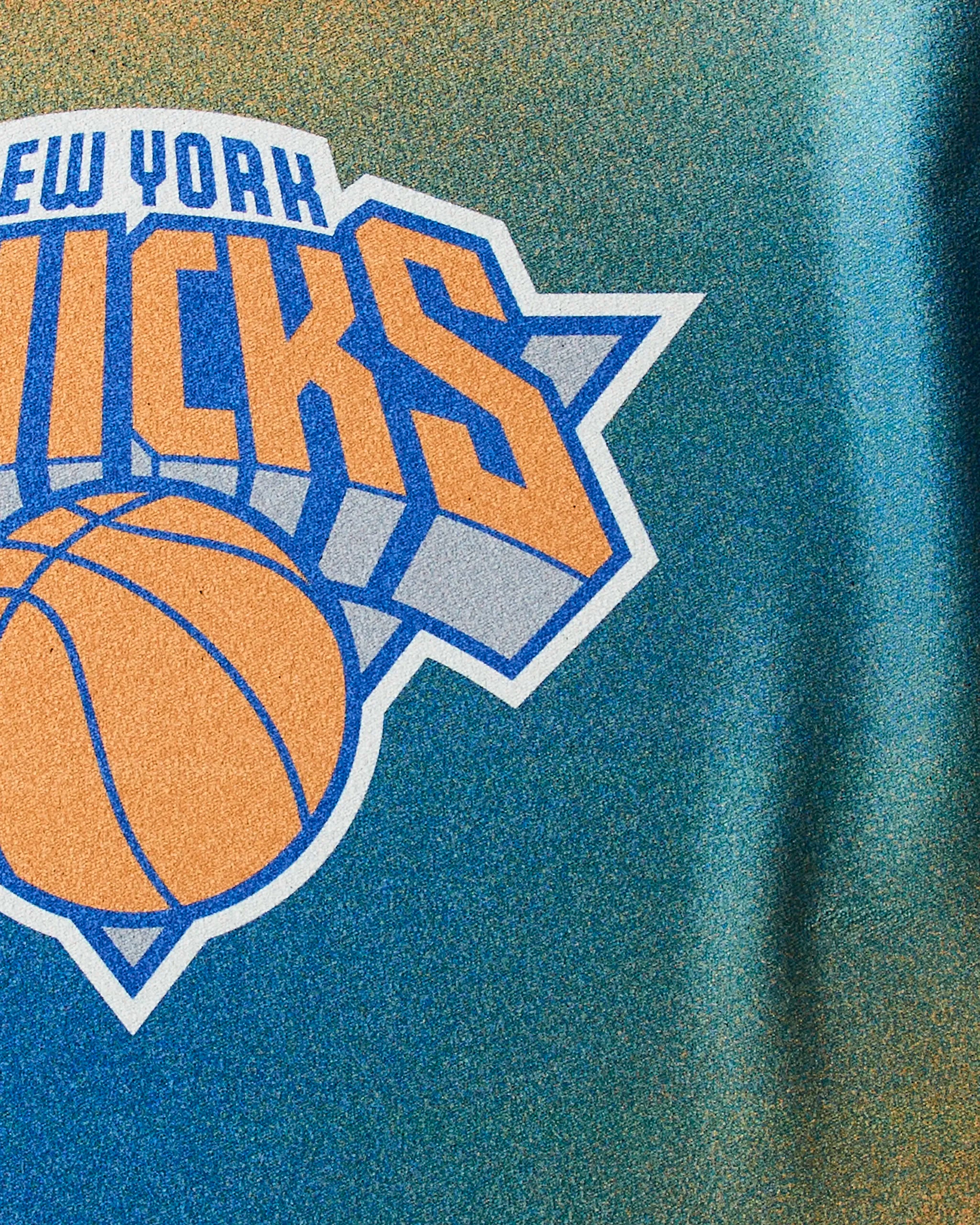 The image showcases Geometry's Knicks Fade towel, featuring the iconic New York Knicks logo with bold orange and blue text and a basketball graphic—ideal as a quick-drying NBA fitness or workout towel.