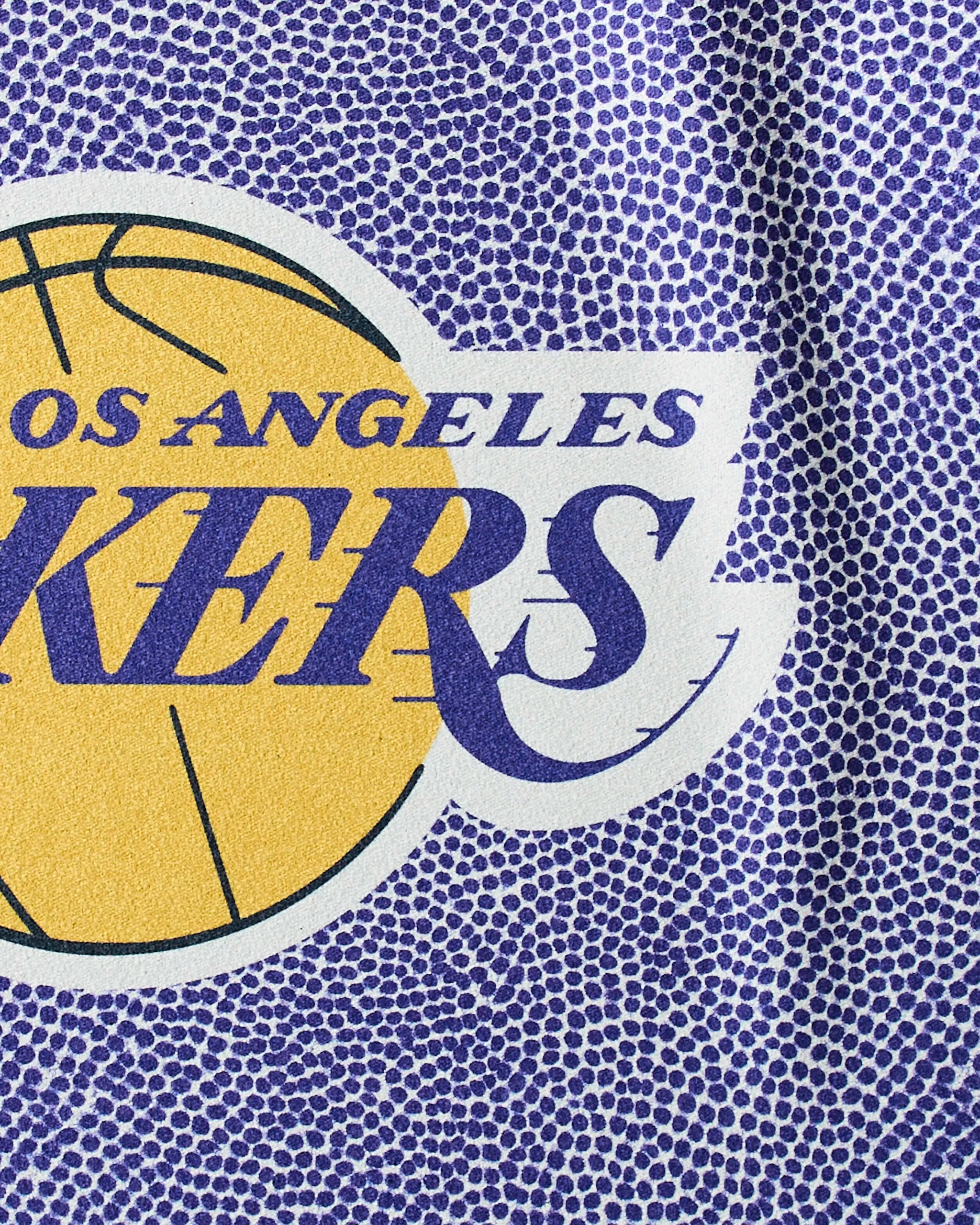 Close-up of the Lakers Grip by Geometry, showcasing the Los Angeles Lakers logo with yellow basketball detail and purple text on a textured, basketball-like purple background—ideal as an NBA fitness towel.