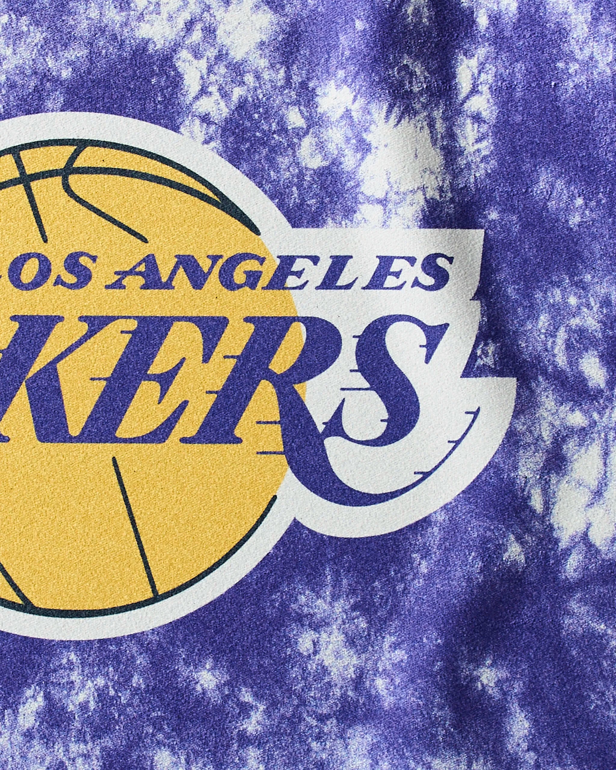 Close-up of the Los Angeles Lakers logo—yellow basketball with bold purple and yellow text—on a purple and white tie-dye, ultra-absorbent fitness towel. Product: Lakers Flash by Geometry.