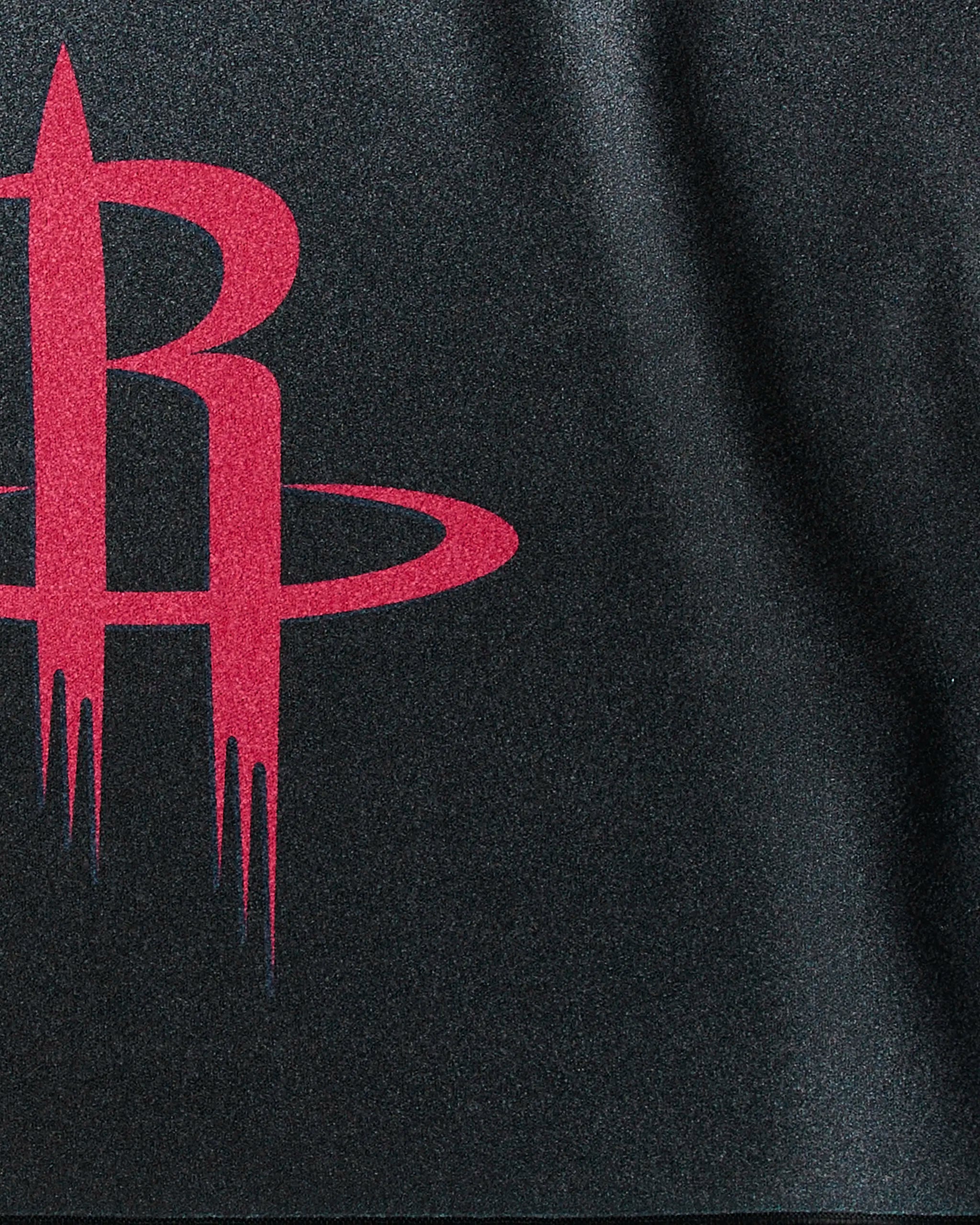 A close-up of the red Rockets Fade logo by Geometry on dark fabric. The stylized "R" with two rings, like a rocket launch, makes this NBA fitness towel perfect for elevating your gym sessions.