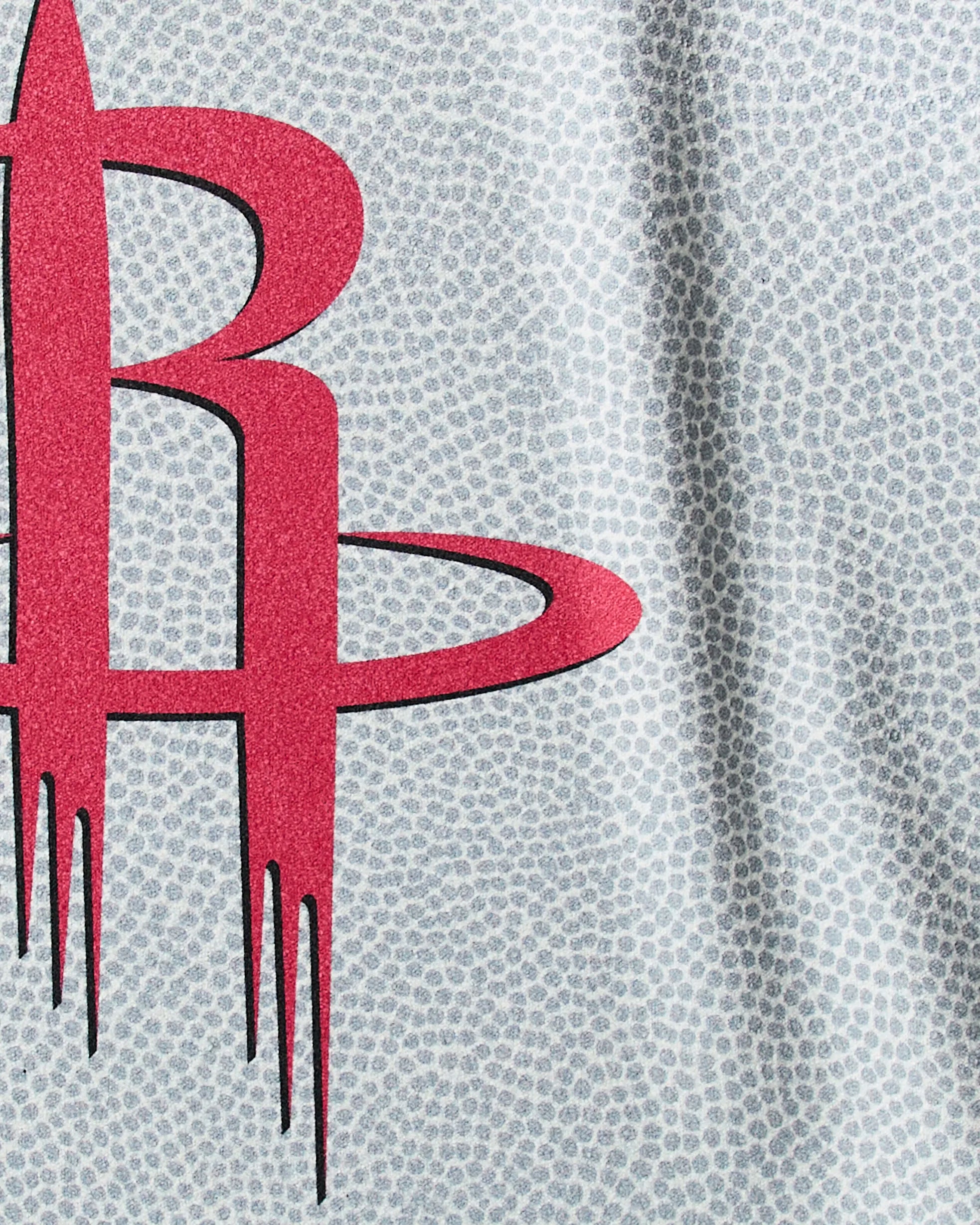 A close-up of a red stylized R logo with vertical streaks on a light gray, dotted background—a bold design by Geometry for the Rockets Grip quick-drying gym or NBA fitness towel.