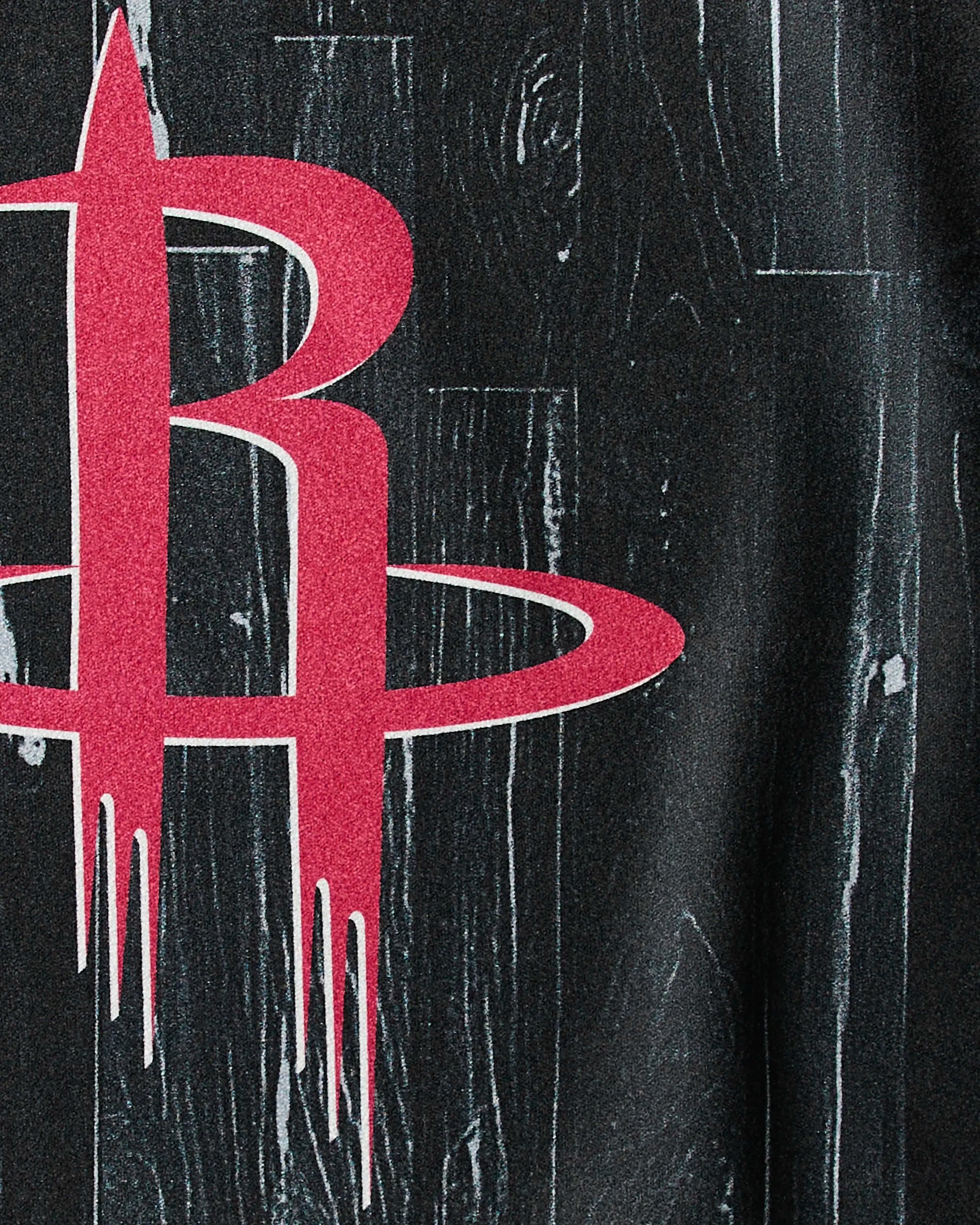 Close-up of the Houston Rockets logo—a red stylized R with a ring—set against dark wood, featured on Geometry's "Rockets Zone" NBA fitness or quick-drying workout towel.