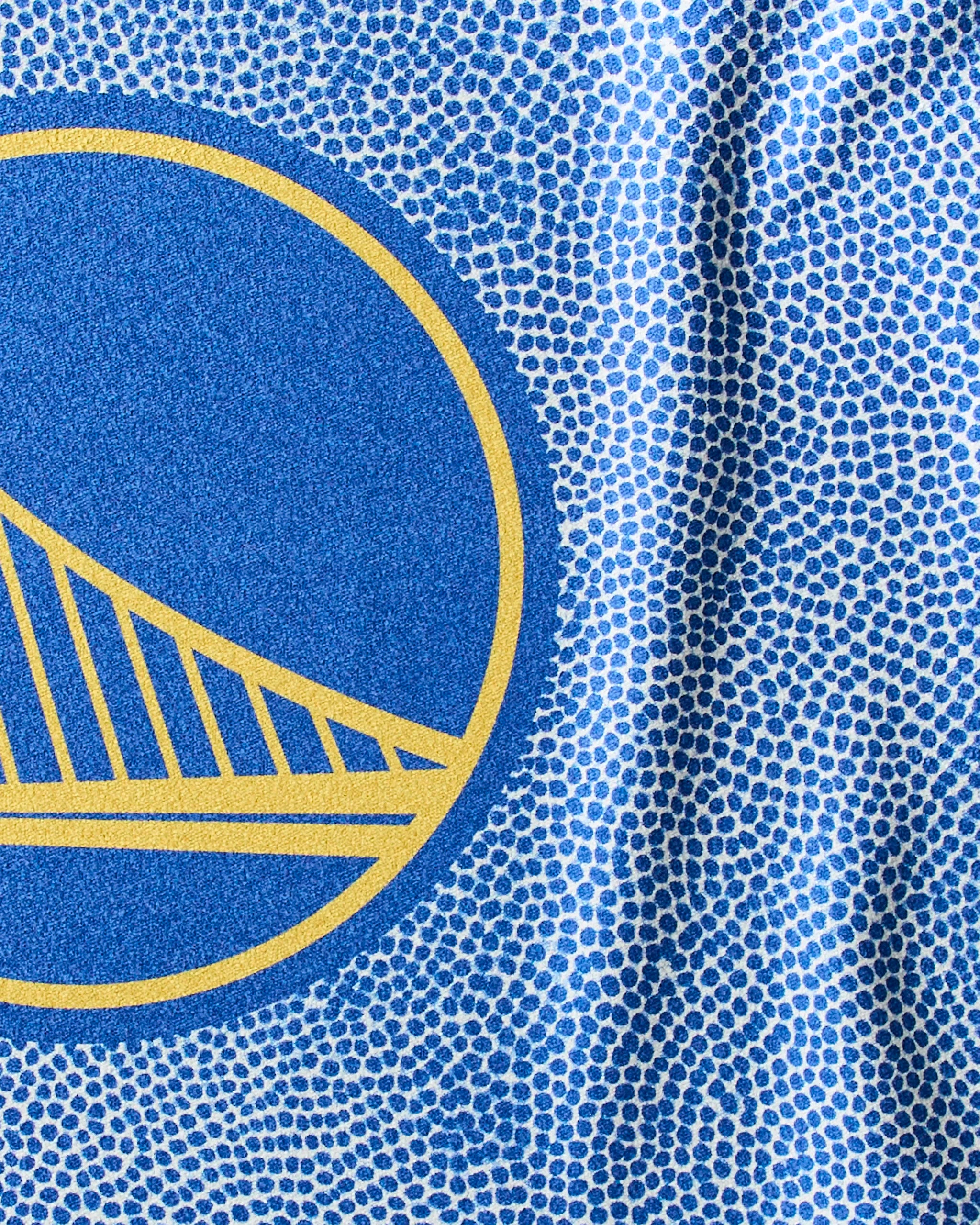 Close-up of the Warriors Grip quick-dry workout towel by Geometry, featuring part of the Golden State Warriors logo in yellow and blue on a dotted blue and white background.