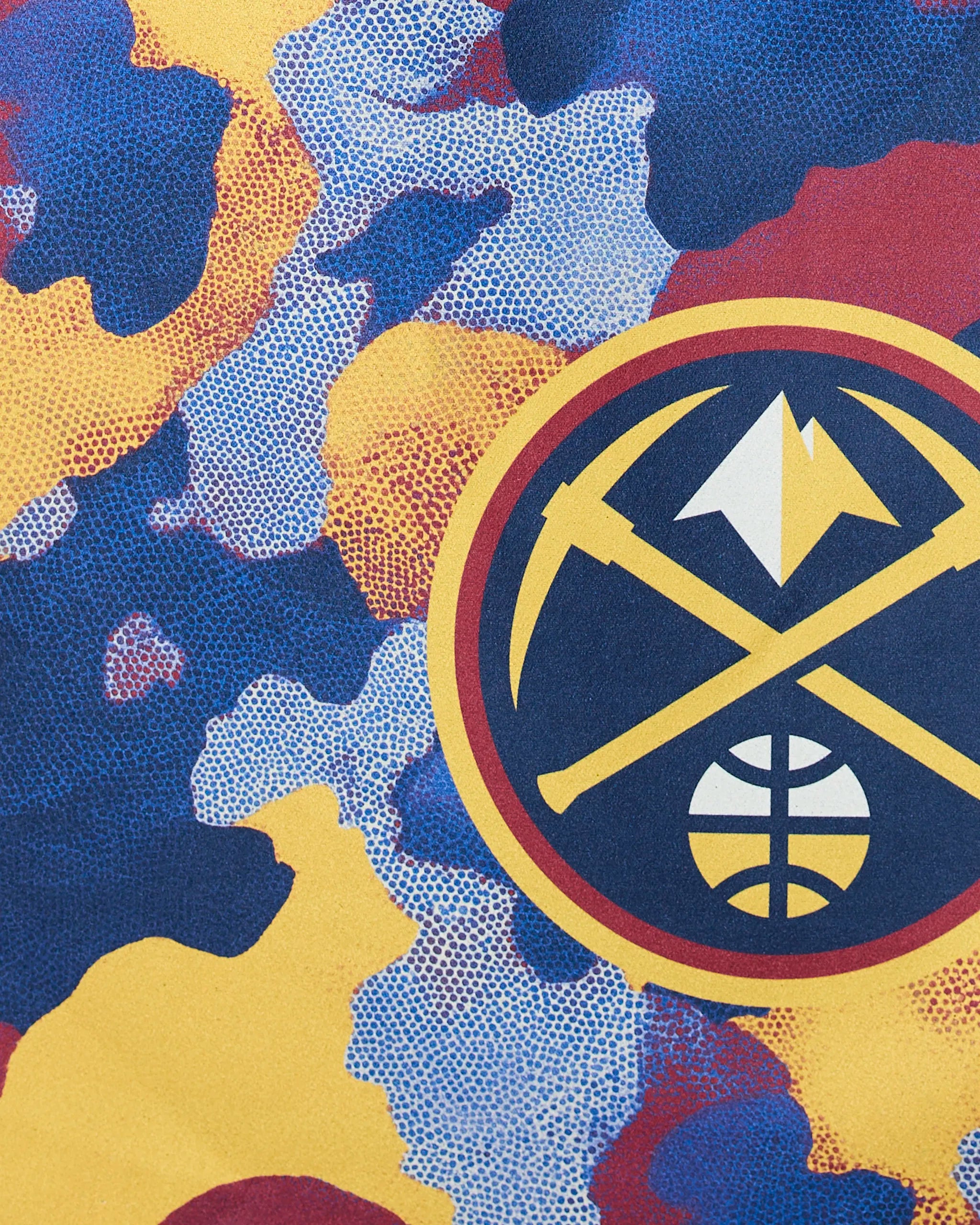 The Nuggets Camo by Geometry features the Denver Nuggets logo with crossed pickaxes, a mountain, and basketball set against a vibrant blue, yellow, and red camouflage background.