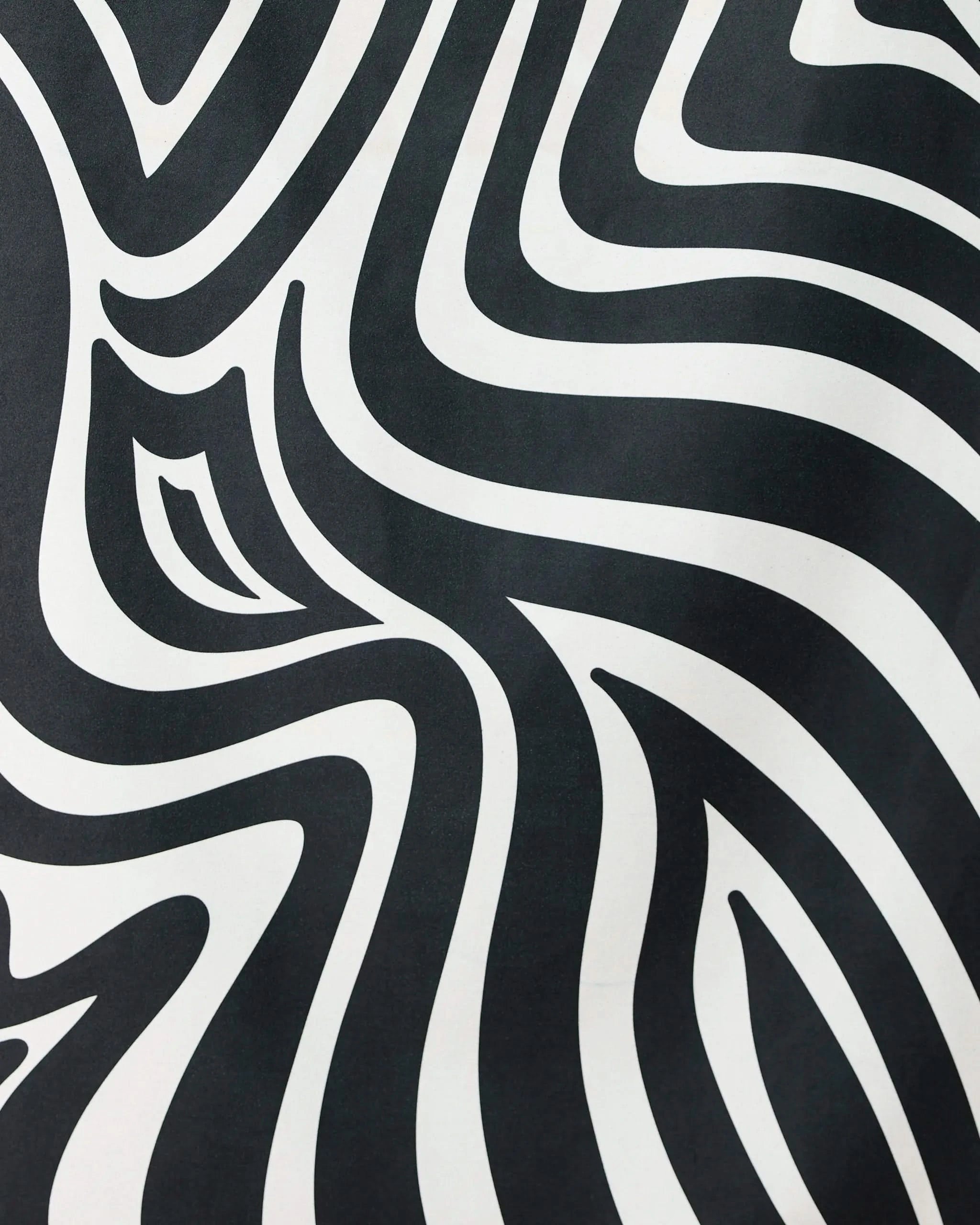 The Dizzy Black quick-drying beach towel by GEOMETRY features bold, wavy black and white zebra-like stripes, creating an eye-catching optical illusion that blends standout style with practical function.