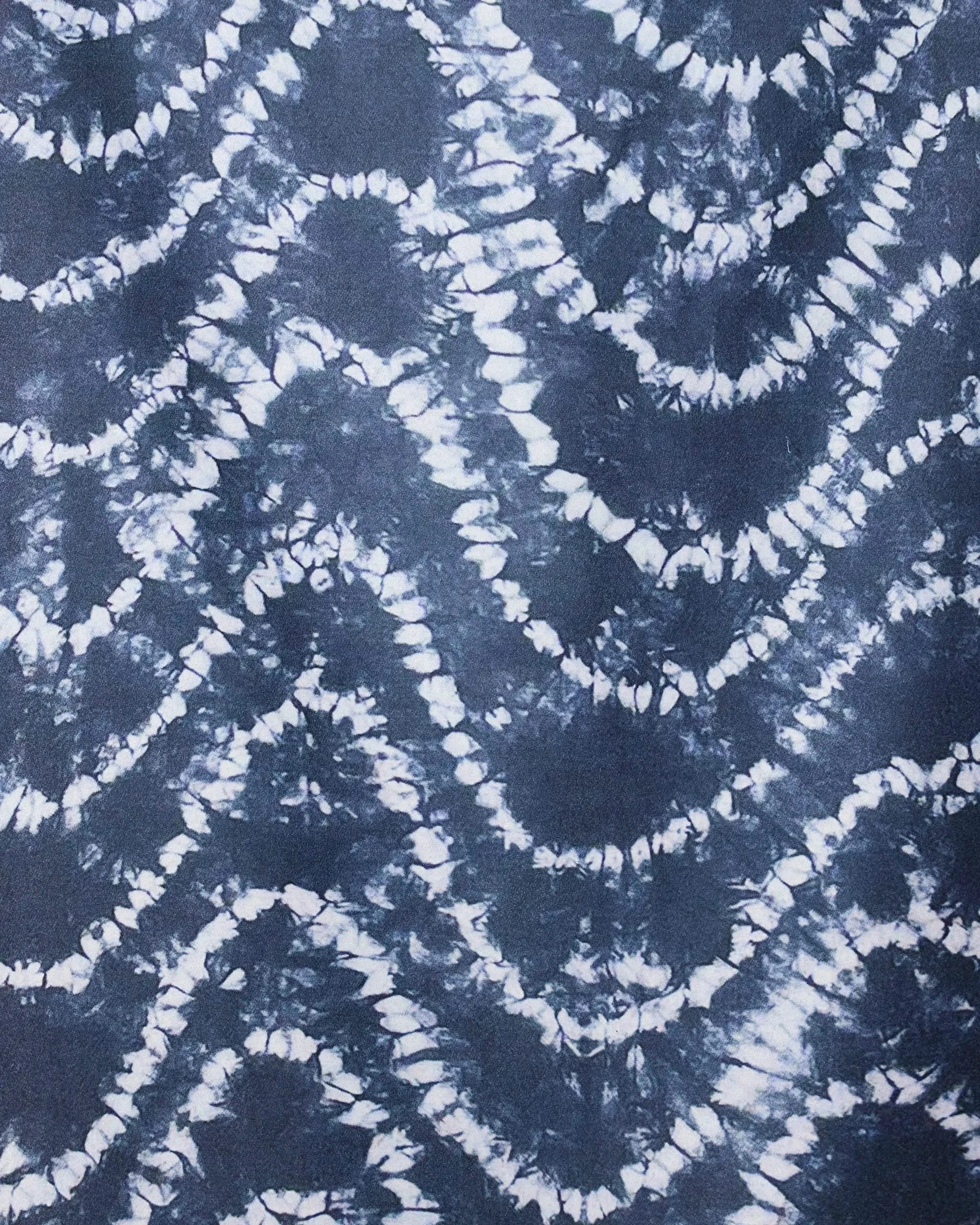 The GEOMETRY Shibo Waves Micro-loop Beach Towel features an abstract tie-dye pattern of dark blue and white zigzag waves. Its modern, textured design is perfect for quick drying and adding style to any beach day.