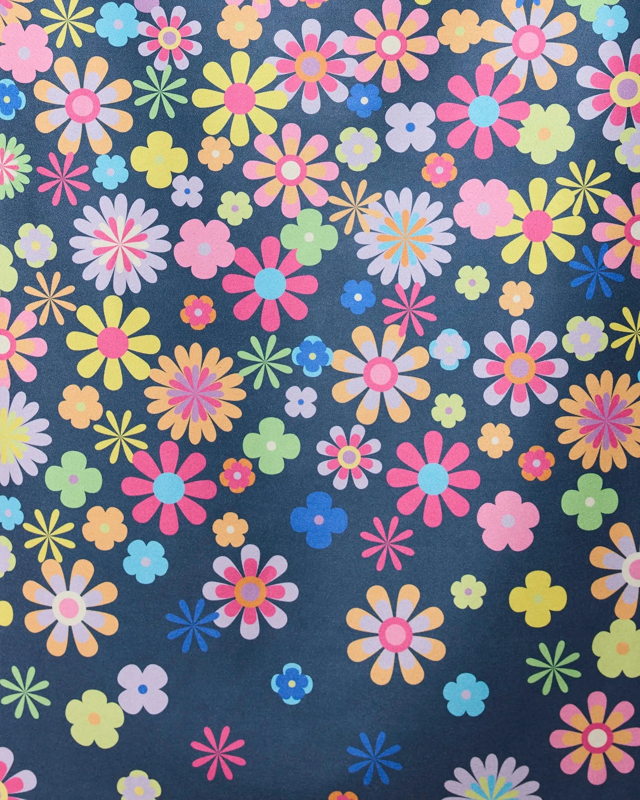 The Far Out Flowers Dark beach towel by GEOMETRY features quick-drying fabric and a bright, playful floral pattern with cartoon-style pink, yellow, blue, orange, and purple flowers on a dark background.