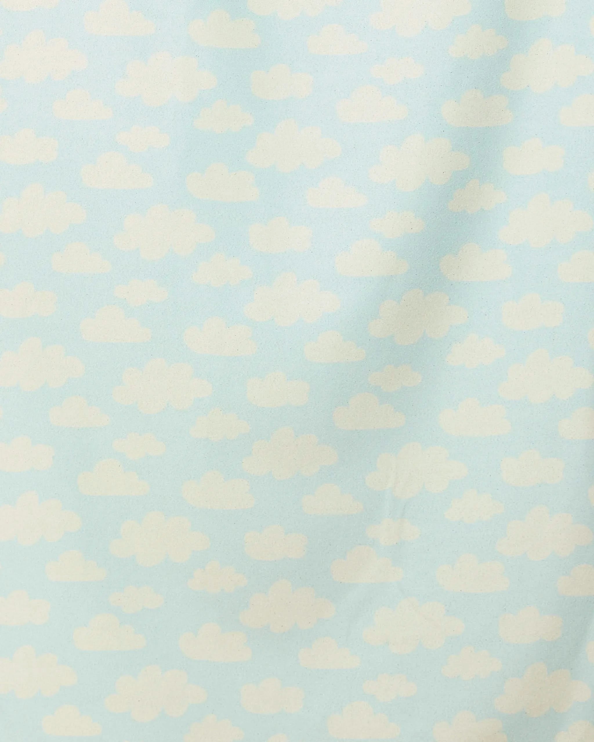 “Made In The Shade” by GEOMETRY features a light blue background with evenly spaced, fluffy white clouds—a whimsical pattern reminiscent of a cartoon sky. This quick-drying beach towel brings playful charm to your seaside days.