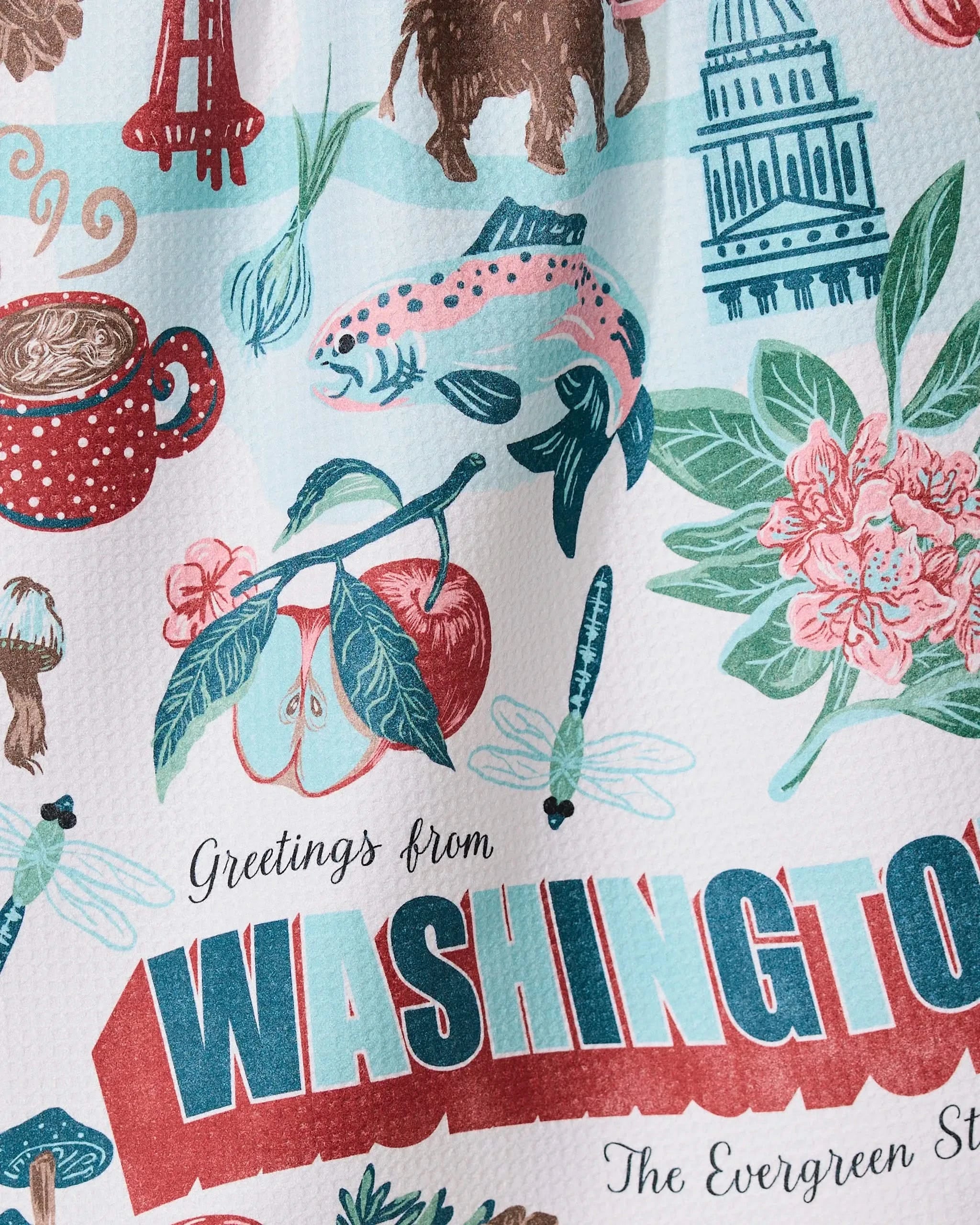 The Geometry Greetings From Washington tea towel features ultra-absorbent fabric and colorful illustrations of state symbols like salmon, apples, cherries, Mt. Rainier, the Capitol dome, flowers, and trees with greeting text.