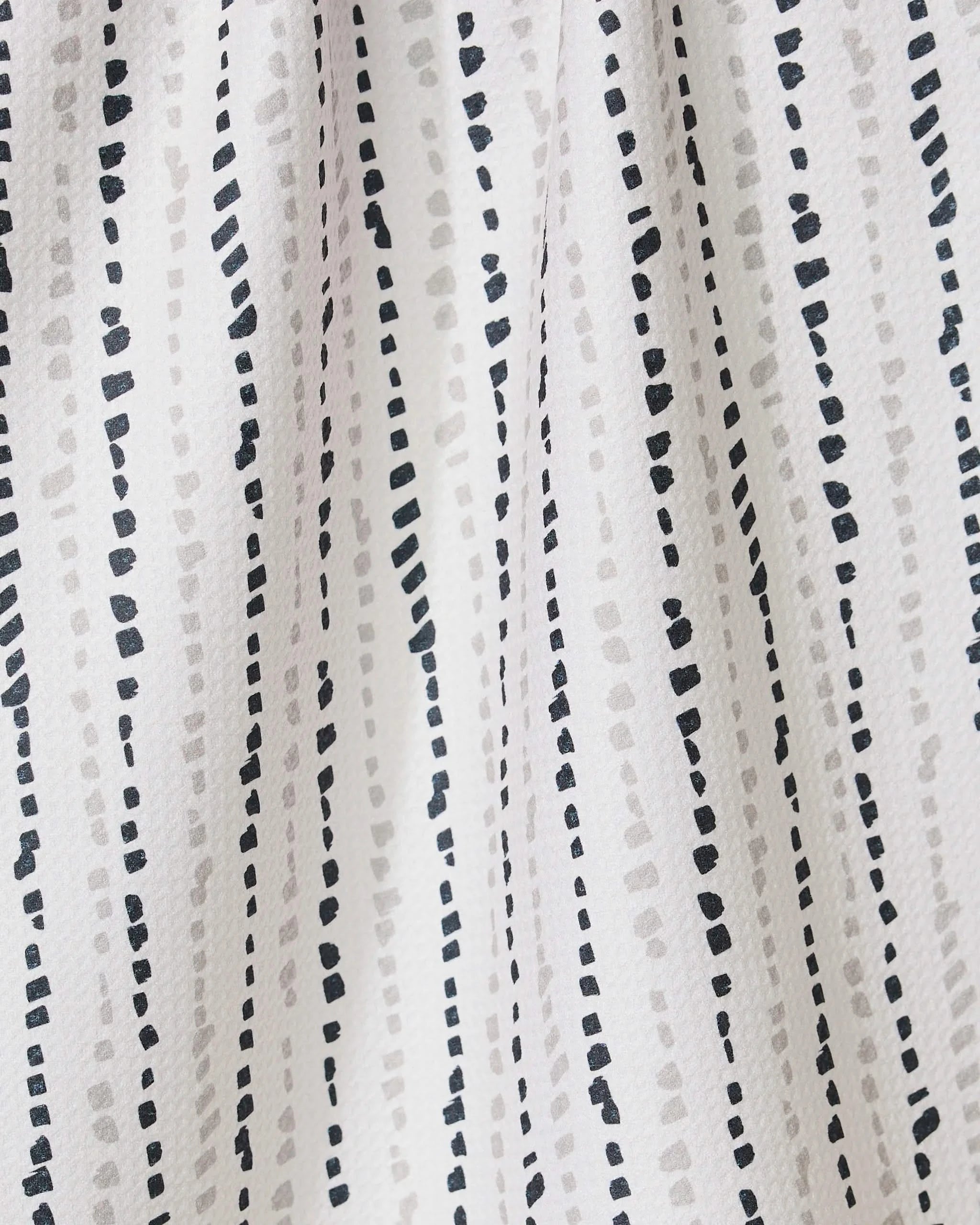 The GEOMETRY Grey Prints recycled kitchen towel features a simple, modern look with white fabric and vertical dotted lines in black and light gray, creating a textured and dynamic appearance.