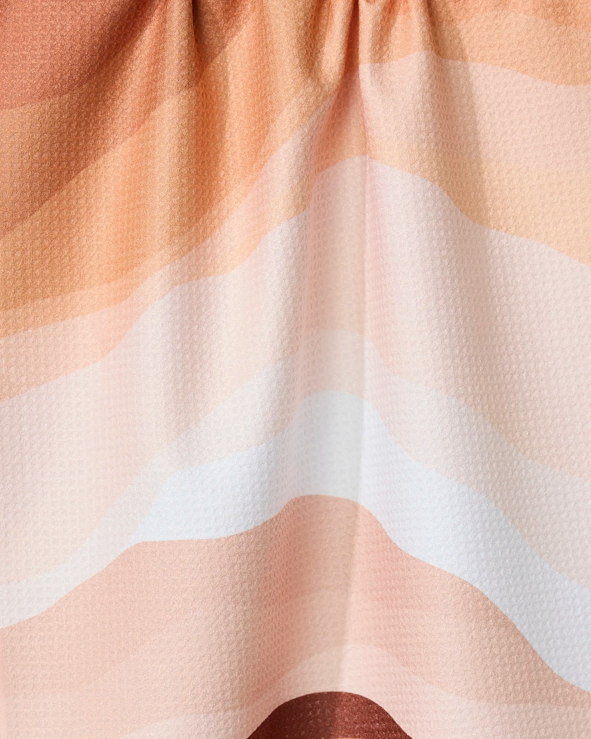 The Levels of Fall tea towel by GEOMETRY features soft, wavy stripes in peach, cream, and white. Made with Geoweave technology, it’s super absorbent with a subtle texture and gentle folds for a relaxed look.