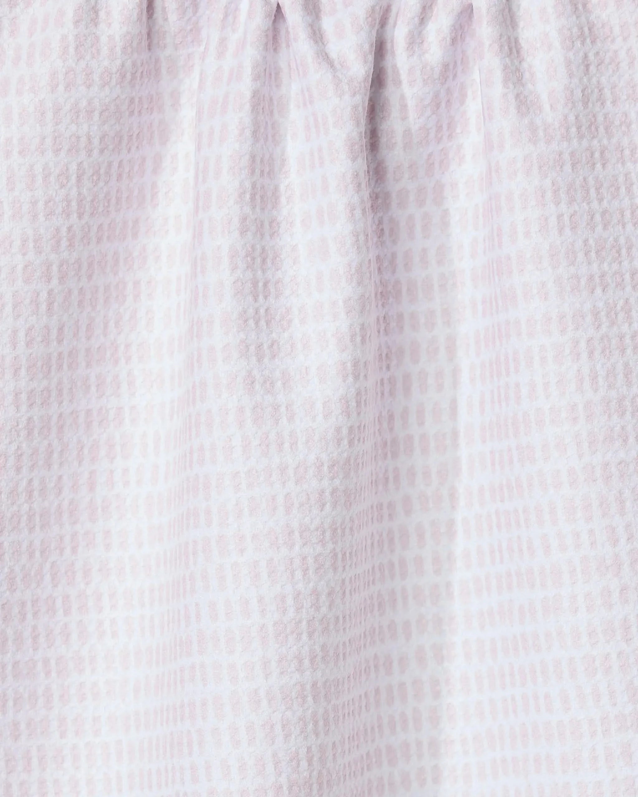 Close-up of Geometry’s Dot Dot Dot Blushed Bergamot kitchen towel, made from recycled fabric in light pink and white with a subtle grid-like dotted pattern. The gathered top creates soft folds and a textured look.
