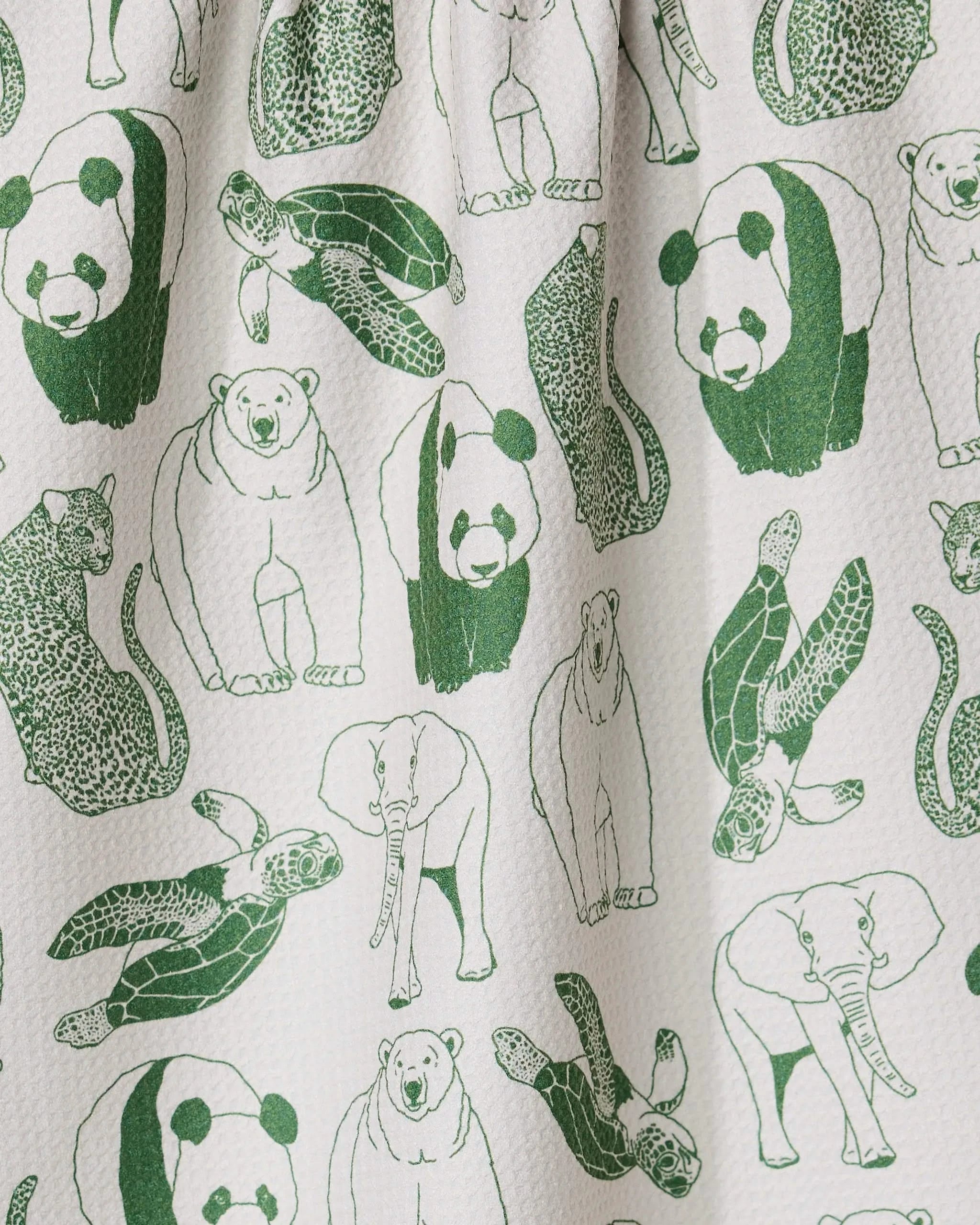 The GEOMETRY Endangered tea towel is white and textured, made from quick-drying recycled material, and features a seamless pattern of green line drawings of pandas, sea turtles, leopards, polar bears, and elephants.