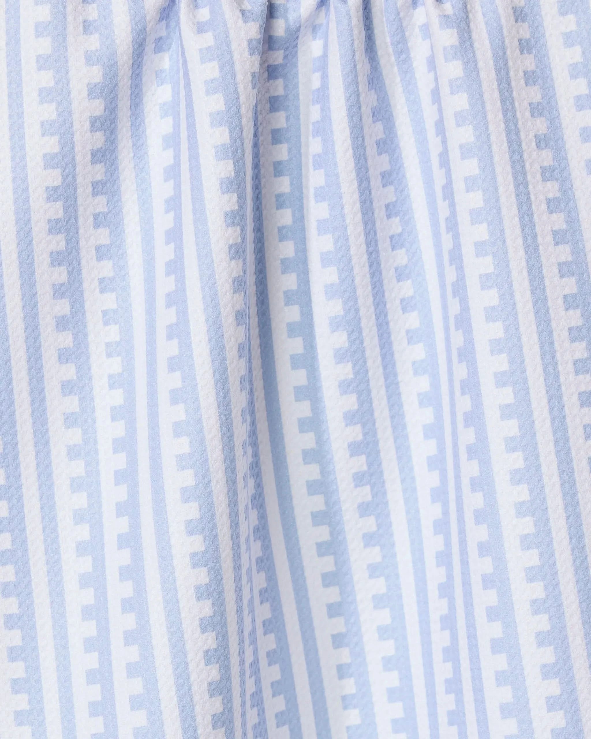 The GEOMETRY Fresh Linen tea towel features soft, gathered light blue and white stripes with a repeating pattern of small rectangles for a modern geometric look and textured feel, perfect for any kitchen.