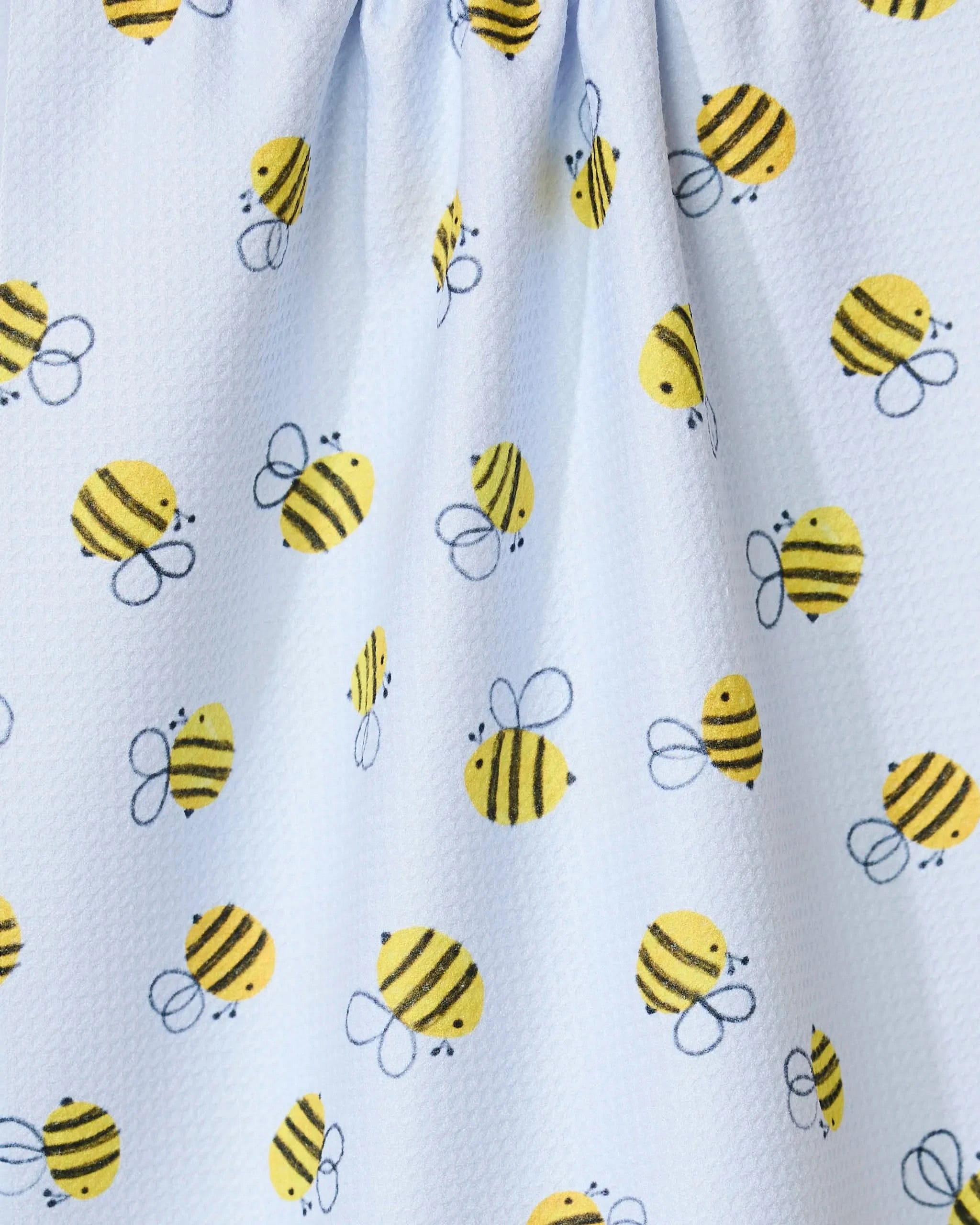 The GEOMETRY Buzzing tea towel features a repeating pattern of cute, cartoon yellow and black bees with wings on white fabric. Eco-friendly and textured, it’s perfect for brightening up any kitchen with its cheerful design.