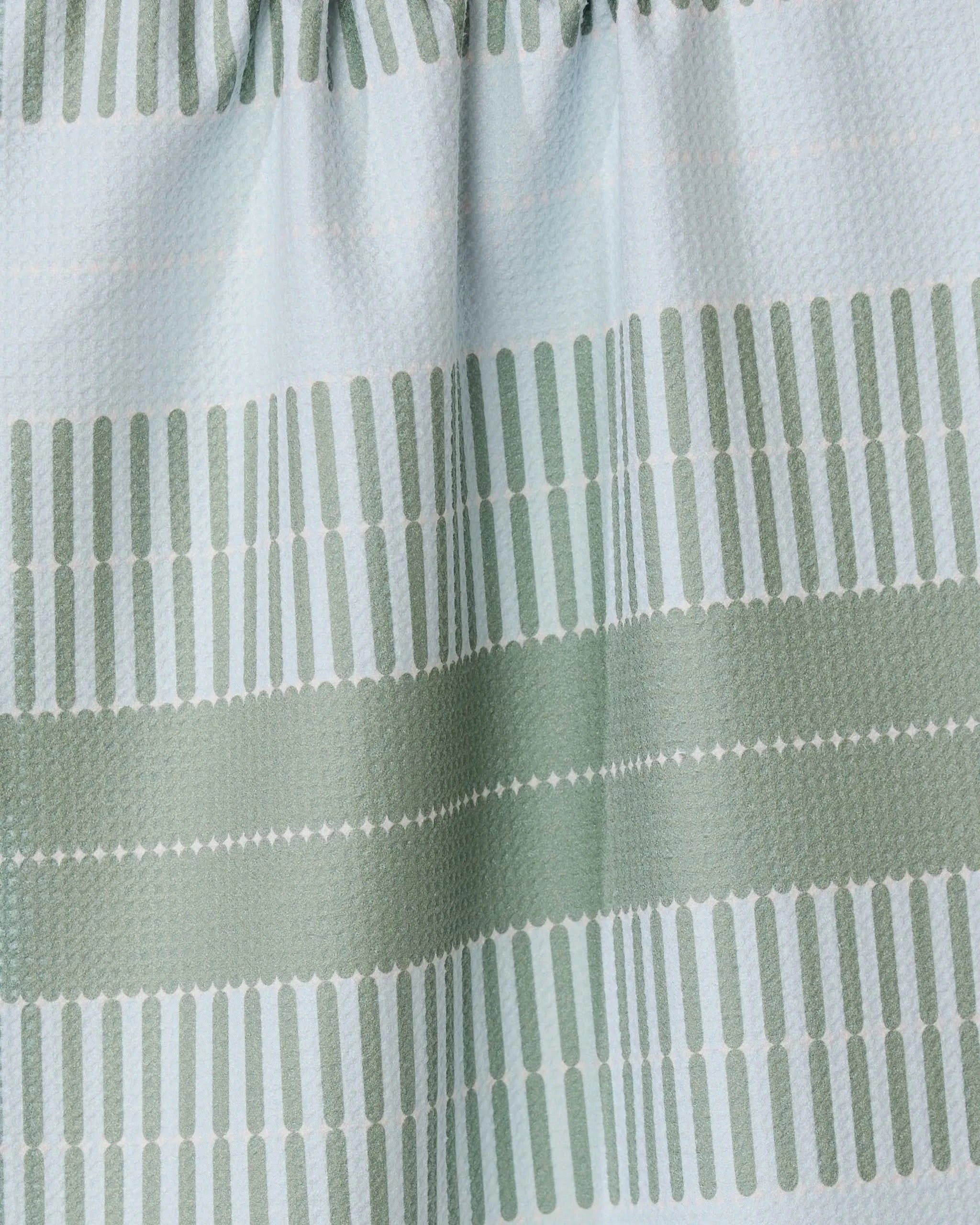 The Bâton Vert tea towel by GEOMETRY features light blue fabric with green horizontal stripes made of small vertical dashes. Its ultra-absorbent, textured material is slightly gathered at the top for a stylish look.