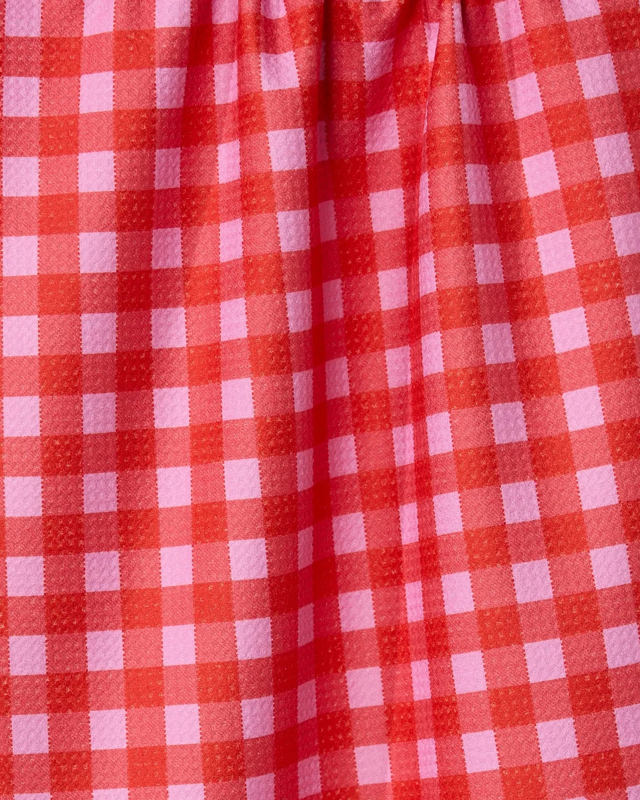 A close-up of GEOMETRYs Cherry Gingham fabric, showcasing its red and pink checkered pattern made from recycled materials with gentle gathers at the top.