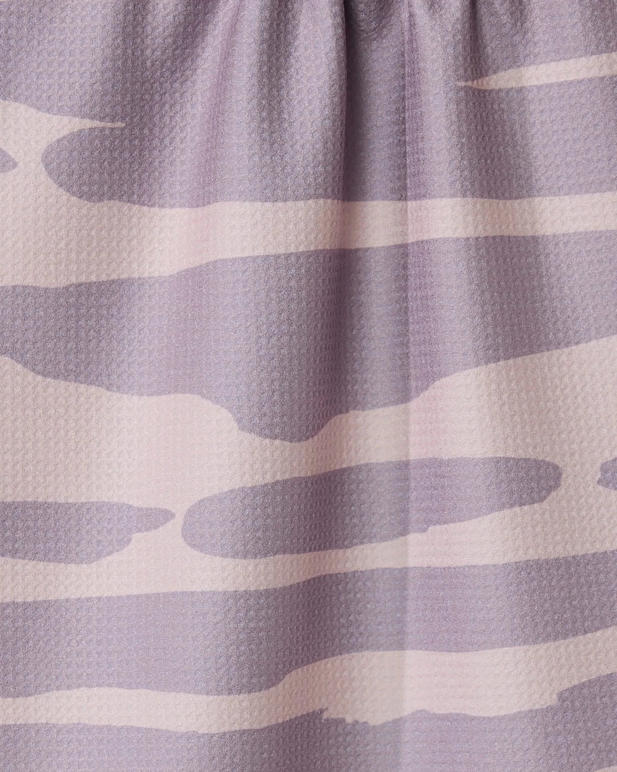 Close-up of the GEOMETRY Reflected - Sunset tea towel, made from recycled materials and featuring a light purple and beige abstract wavy pattern. The fabric is slightly gathered at the top.