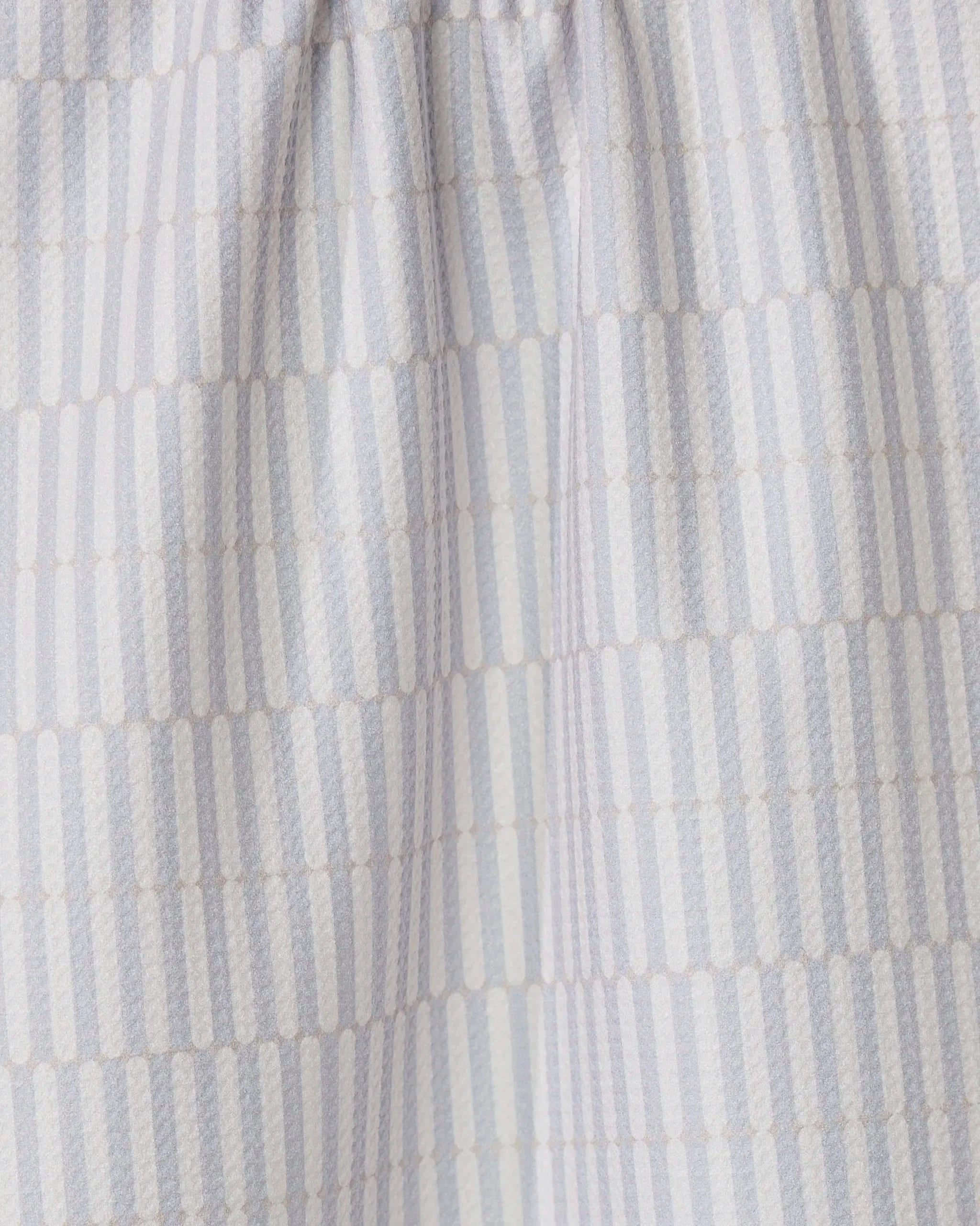 The Rideaux Neutre tea towel by GEOMETRY features white fabric with vertical stripes of small beige dots in a subtle geometric pattern. Slightly gathered at the top, its an eco-friendly and stylish choice for any kitchen.