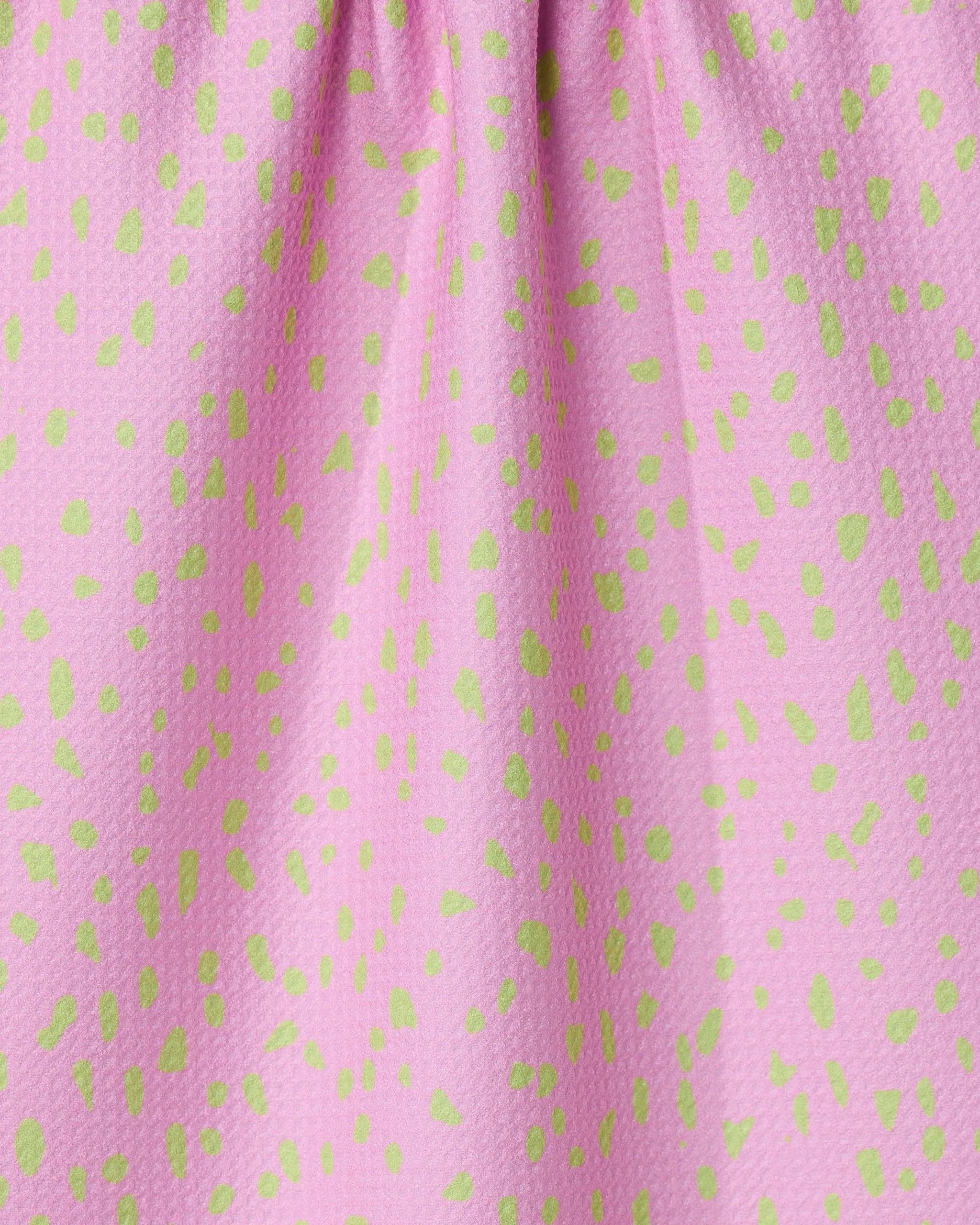 Close-up of GEOMETRYs Speckle Pink tea towel, made from recycled materials and featuring a pink textured design with small green dots and gathered folds at the top.
