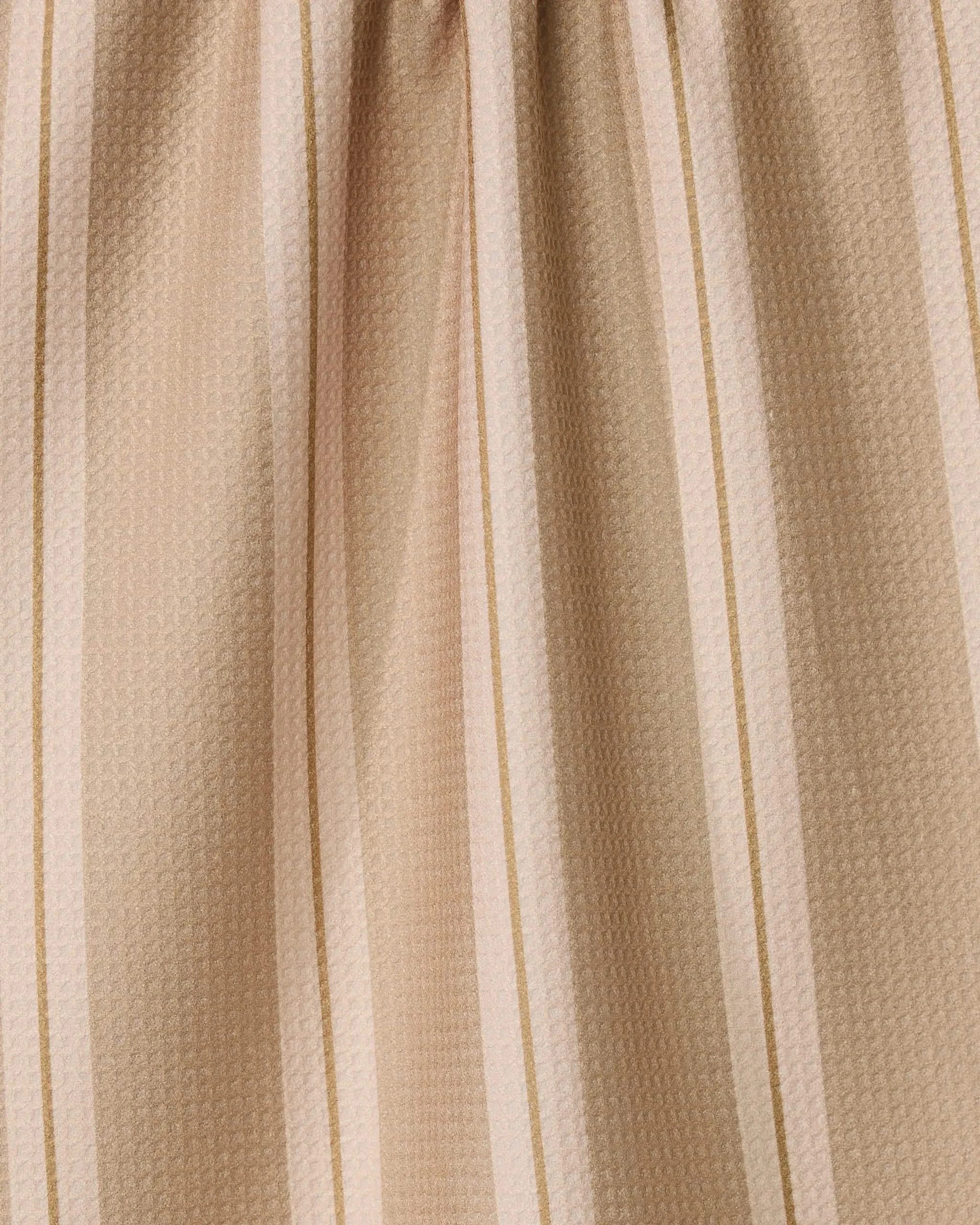 The GEOMETRY Vanilla Chai kitchen towel, made from recycled materials, features beige fabric with light and dark tan stripes, a subtle textured pattern, gentle gathers, and ultra-absorbent performance.