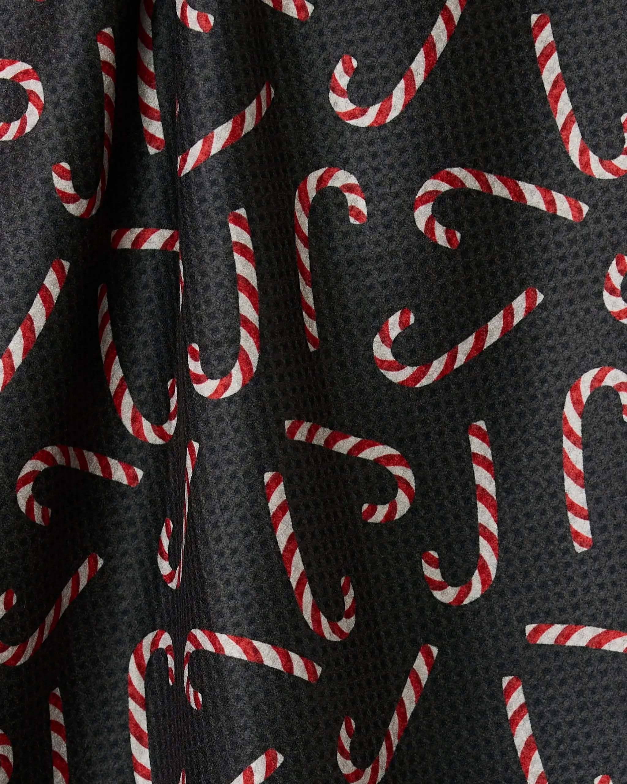 Geometry’s Sweet Canes tea towel features a black double-sided fabric with red and white striped candy canes in every direction, adding festive style and function to your kitchen.