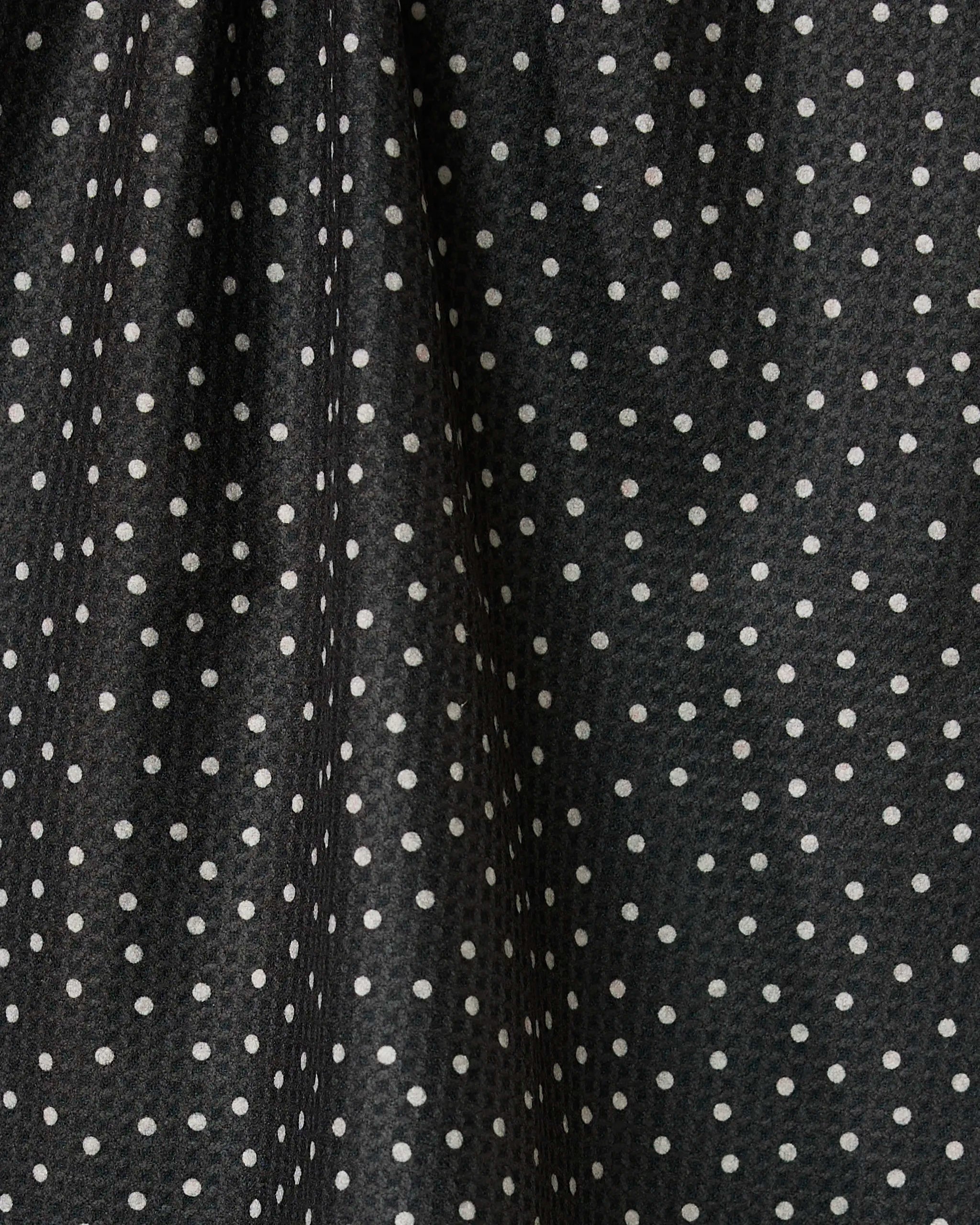 Close-up of the Geometry Sweet Canes tea towel, featuring quick-drying black fabric with evenly spaced white polka dots, soft folds, and a slight sheen that creates subtle texture and shadows.